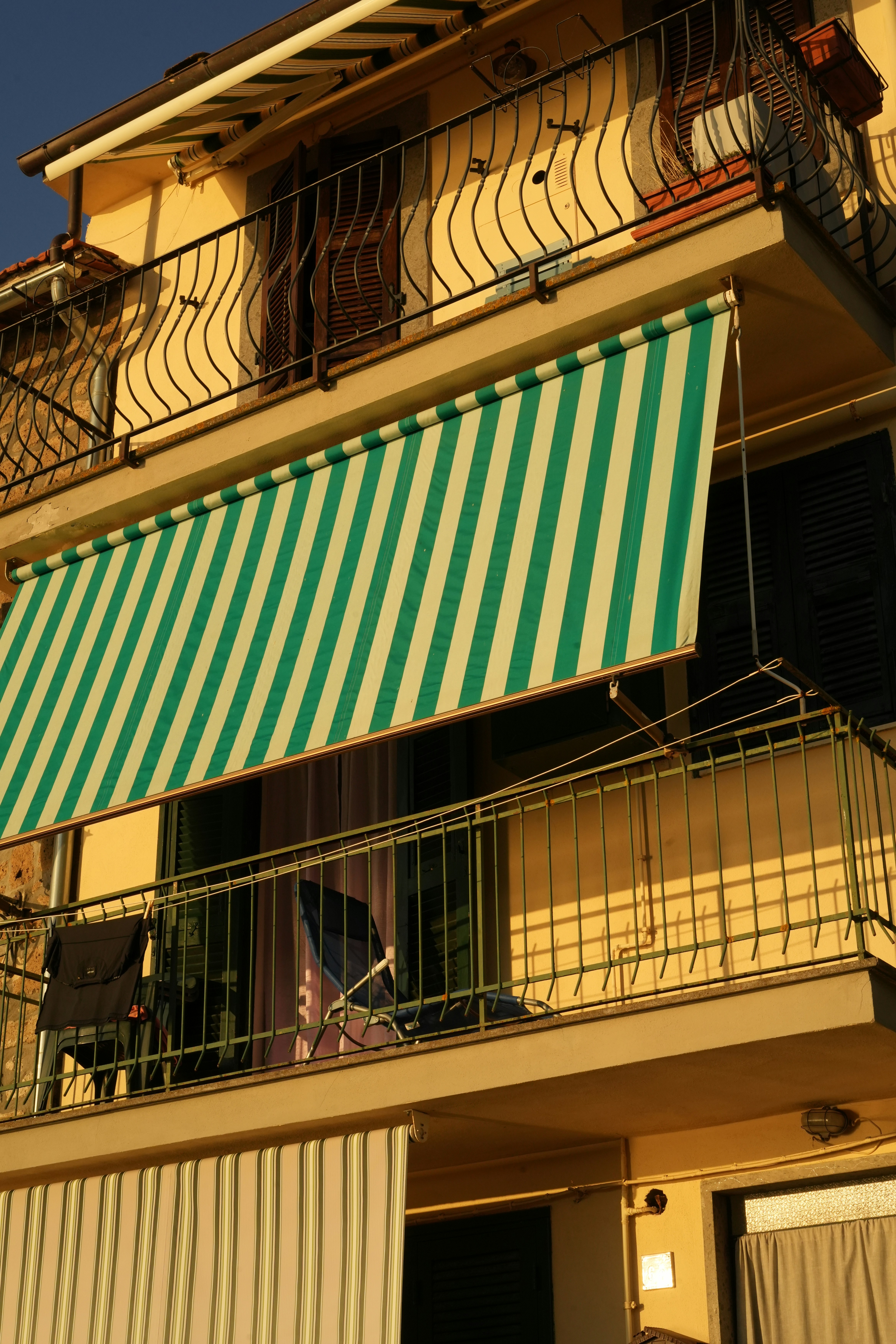 Un auvent rayé vert et blanc sur un balcon.