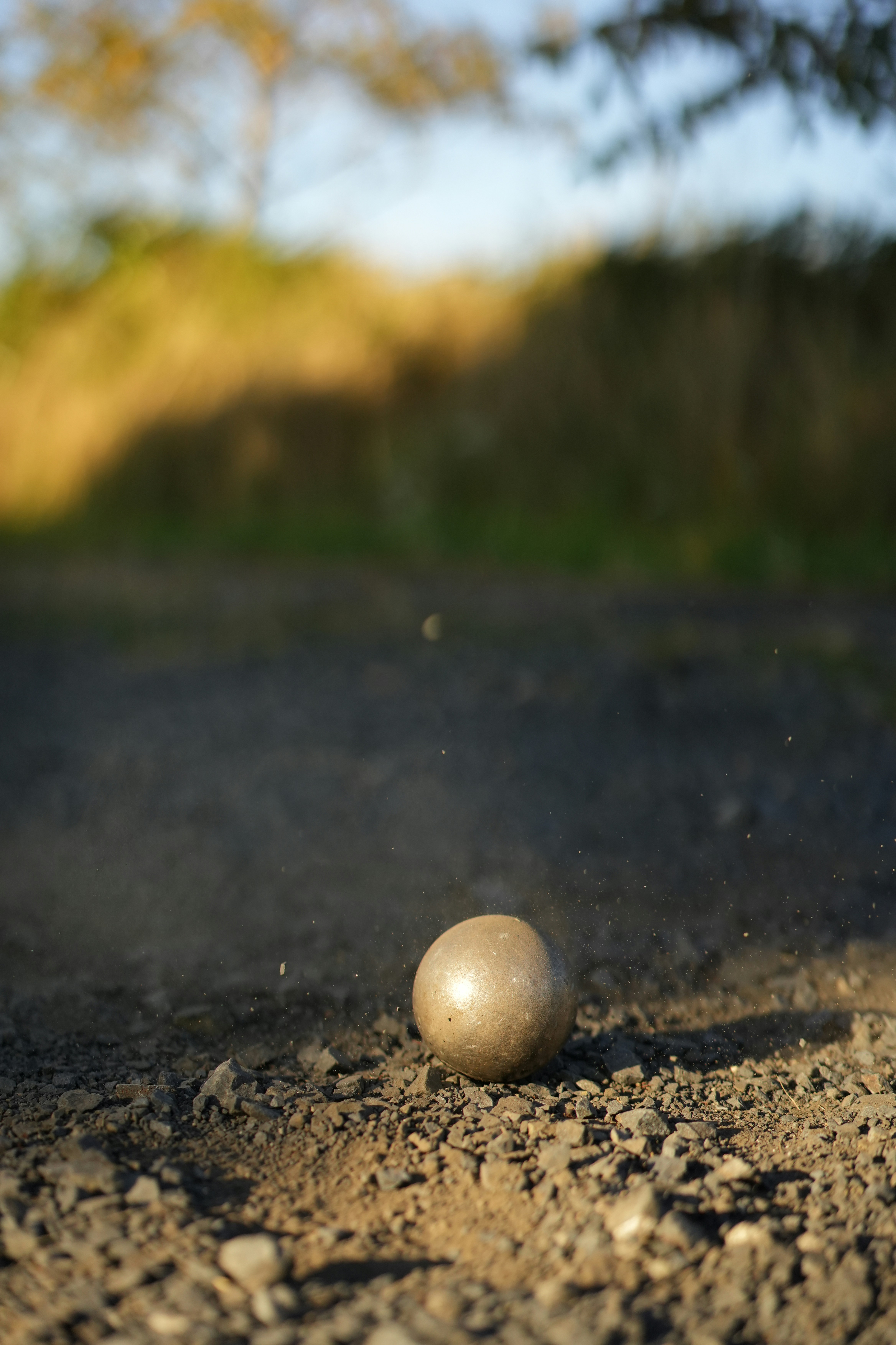 Une boule de métal se trouve sur une route poussiéreuse.