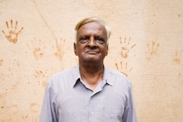 Man poses in front of a wall with handprints.