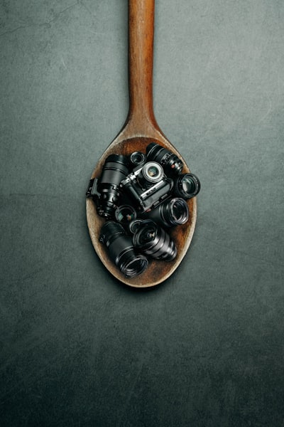 Lenses and a camera sit in a wooden spoon.