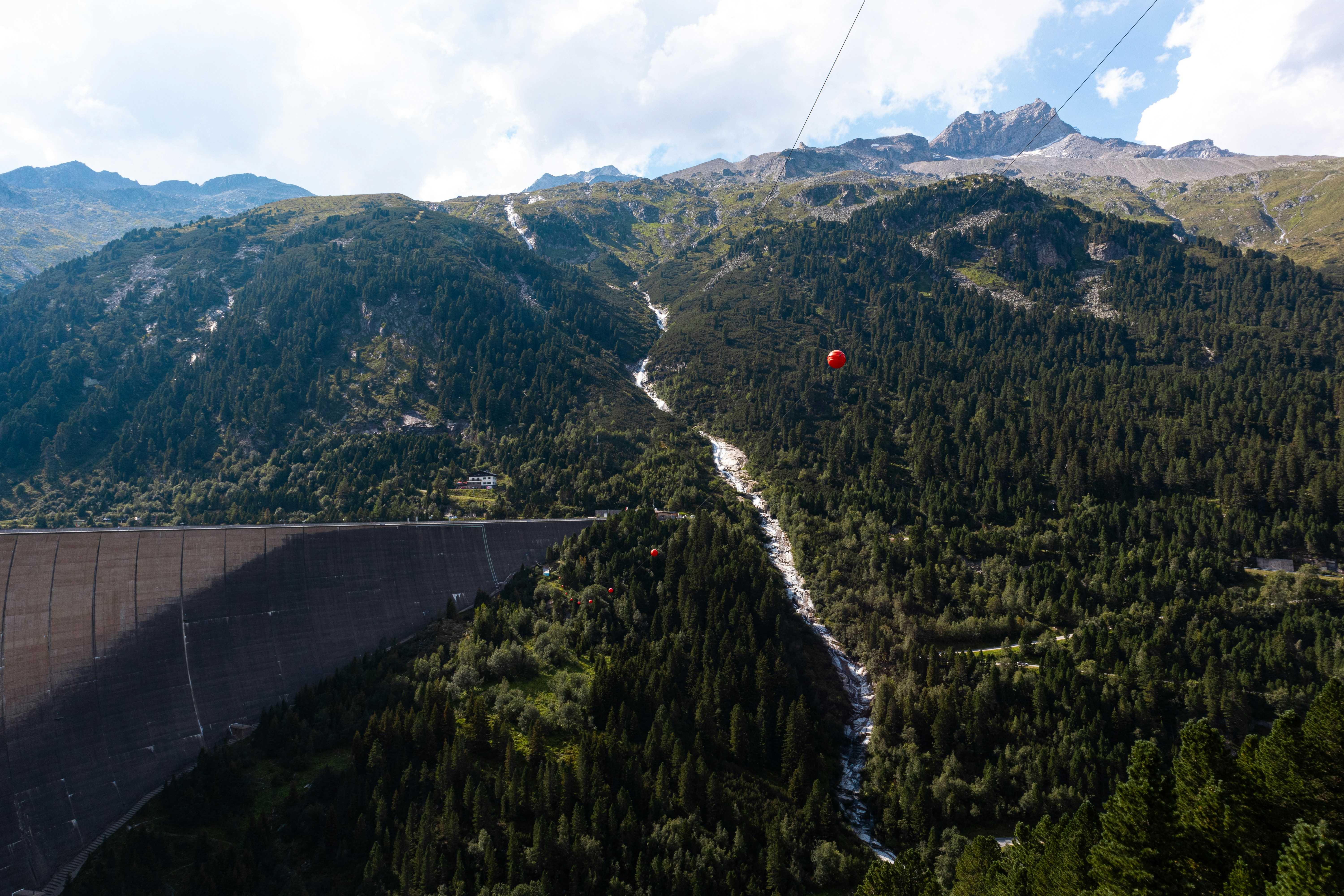 Mountains and a red object over a dam.