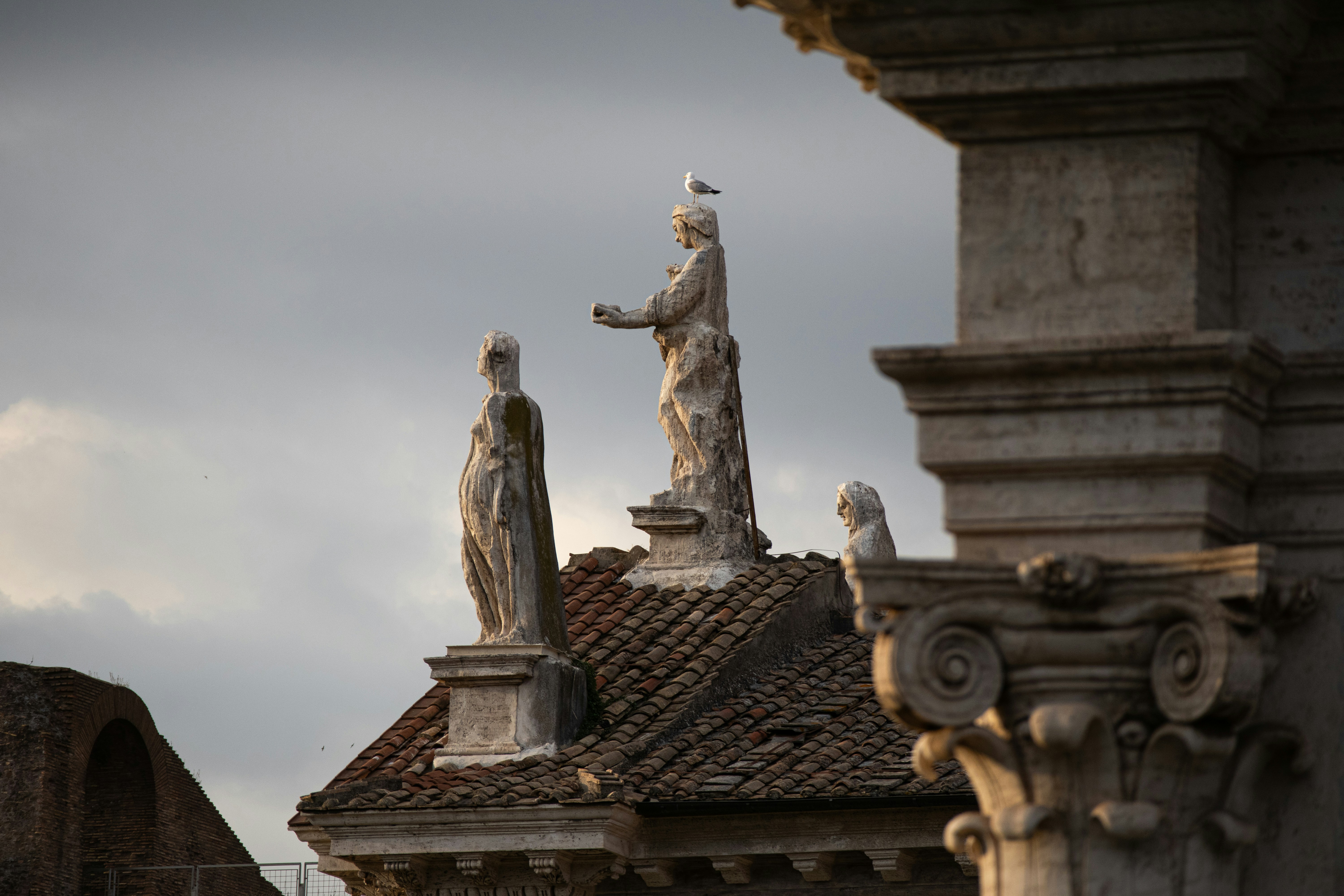 Statues and a bird stand atop a building.