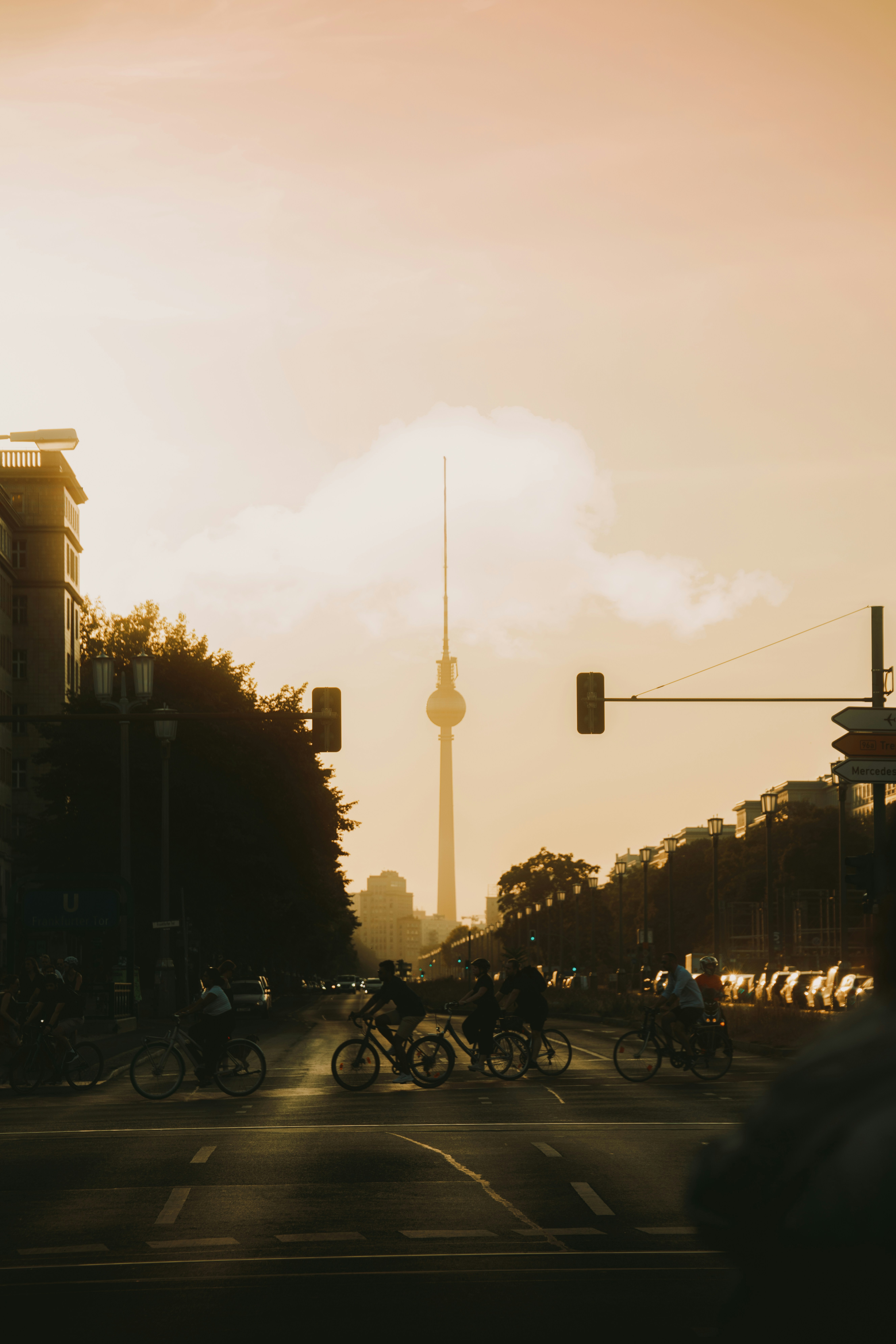 Cyclists ride past a silhouetted cityscape at sunset.