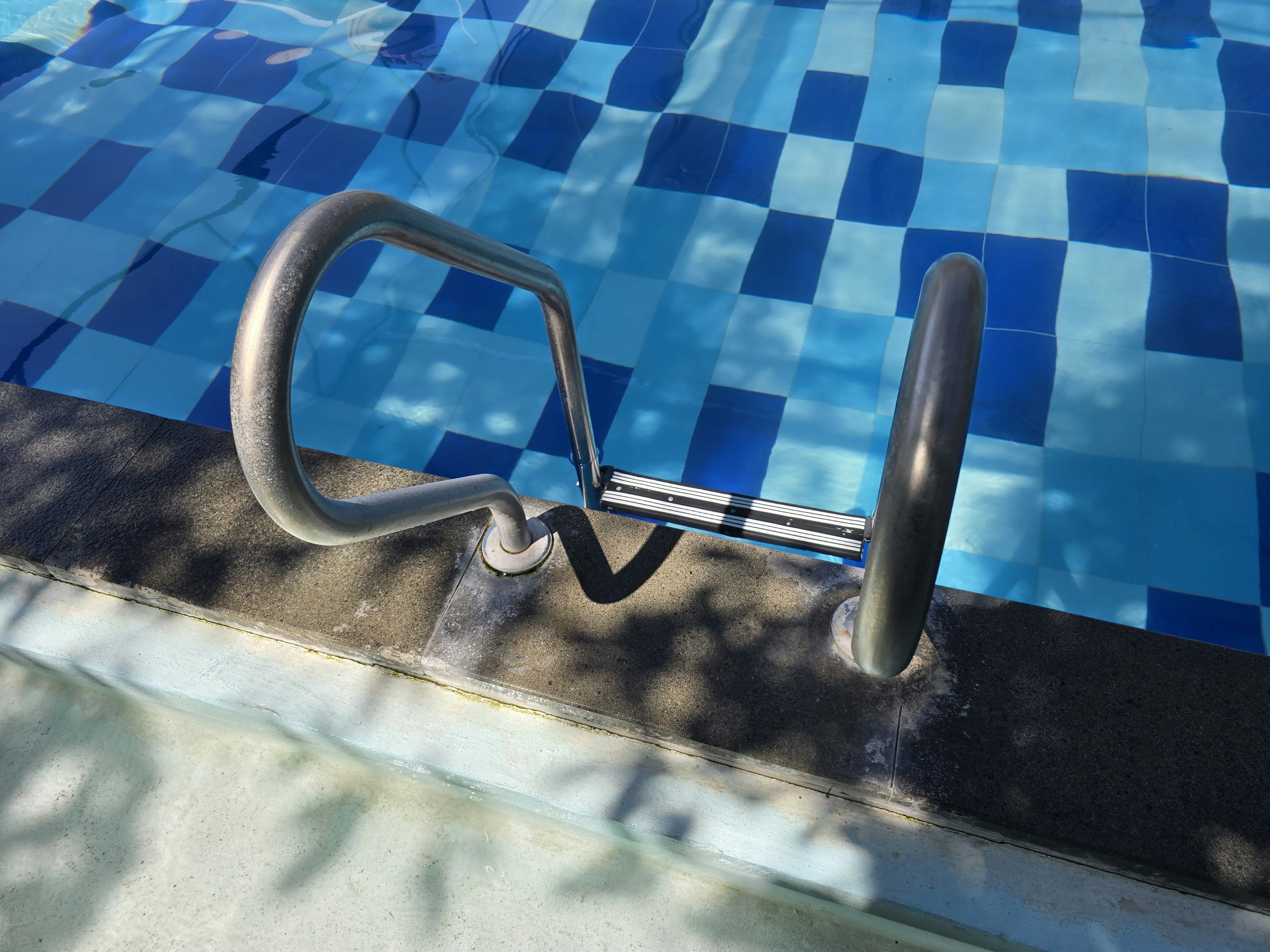Pool ladder leads into clear blue water.