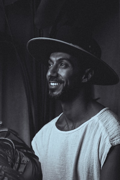 Smiling man in a hat looks off into the distance.