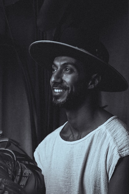 Smiling man in a hat looks off into the distance.