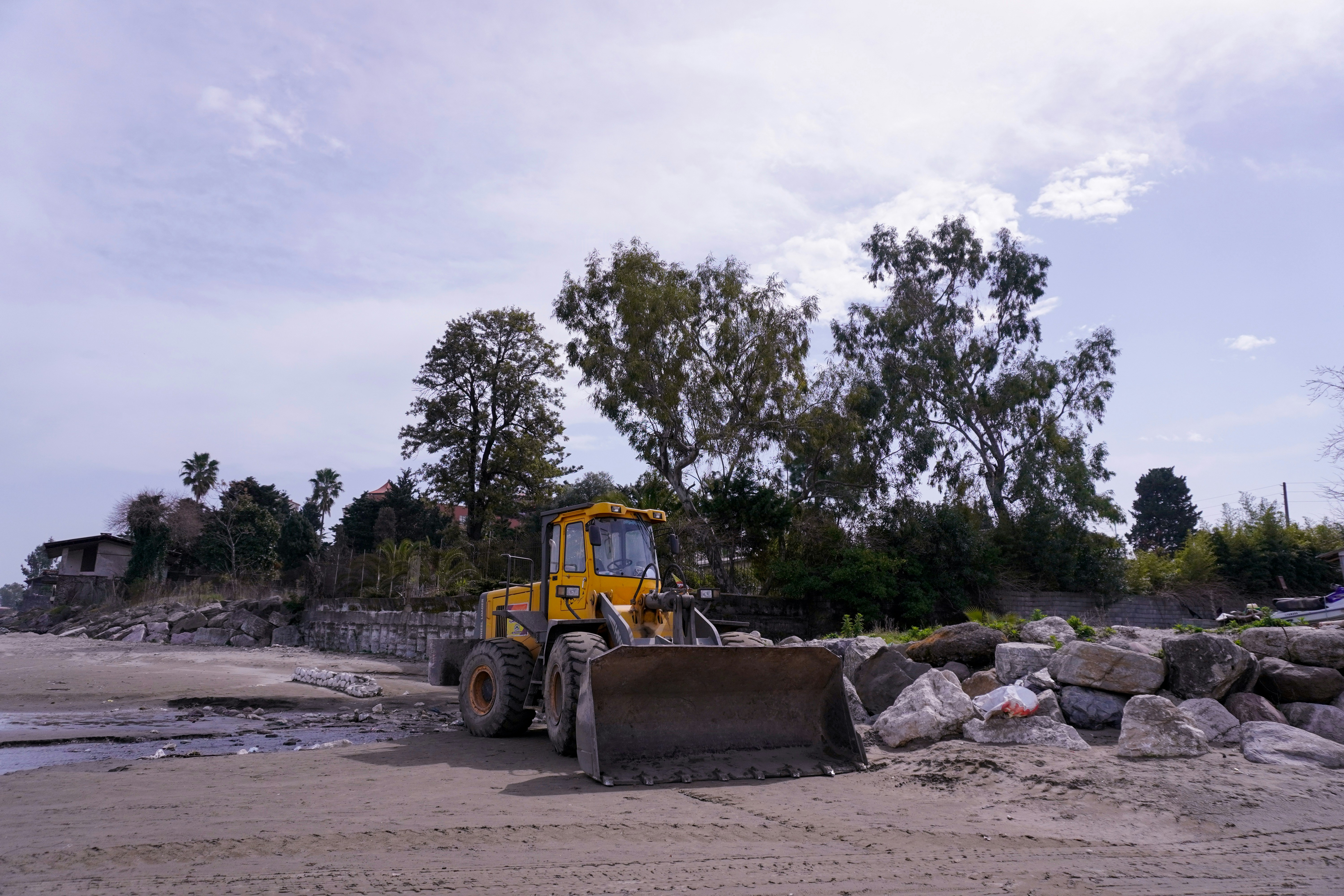 A yellow bulldozer is on a beach.