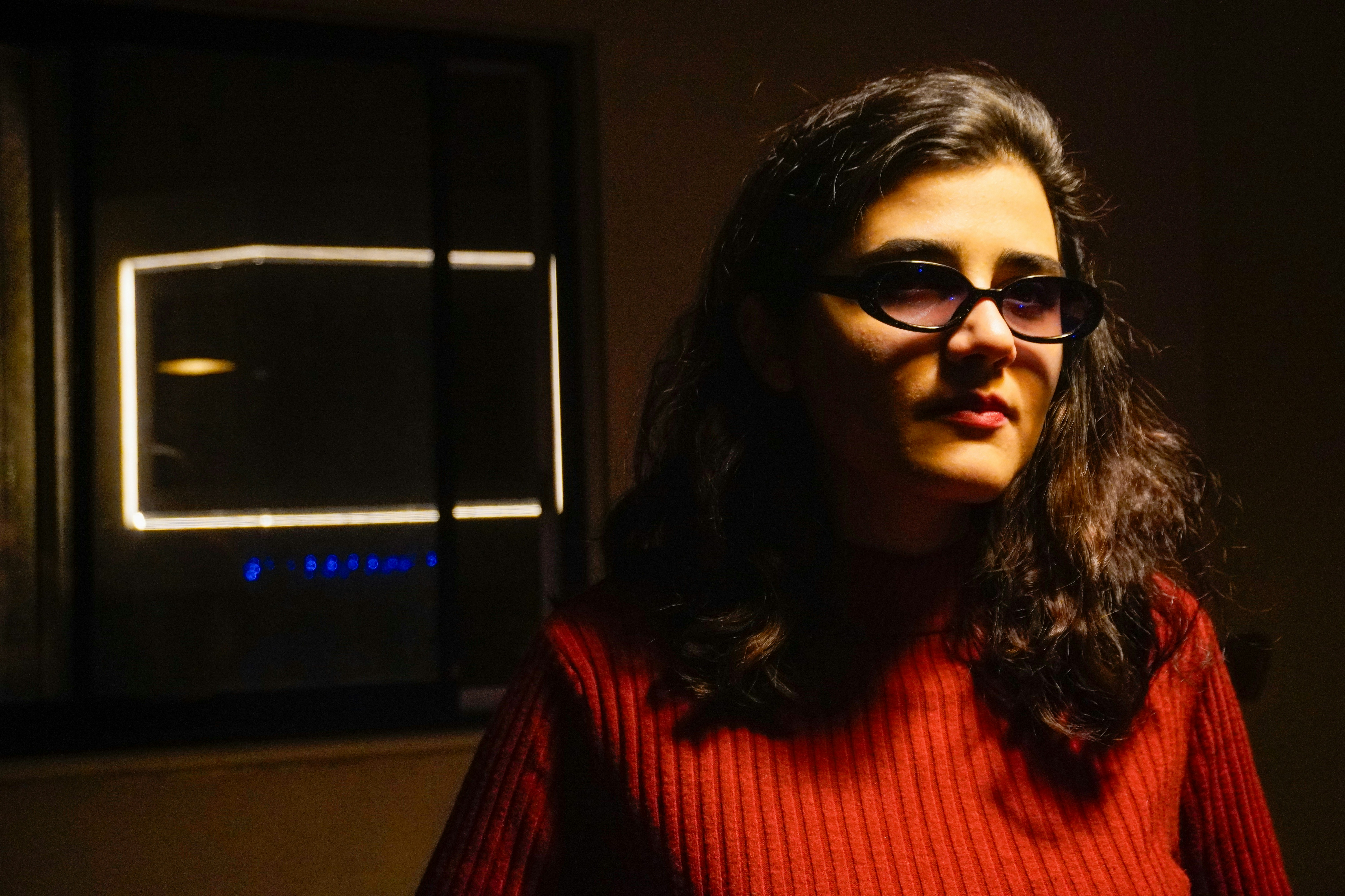 Woman wearing glasses in a dimly lit room.