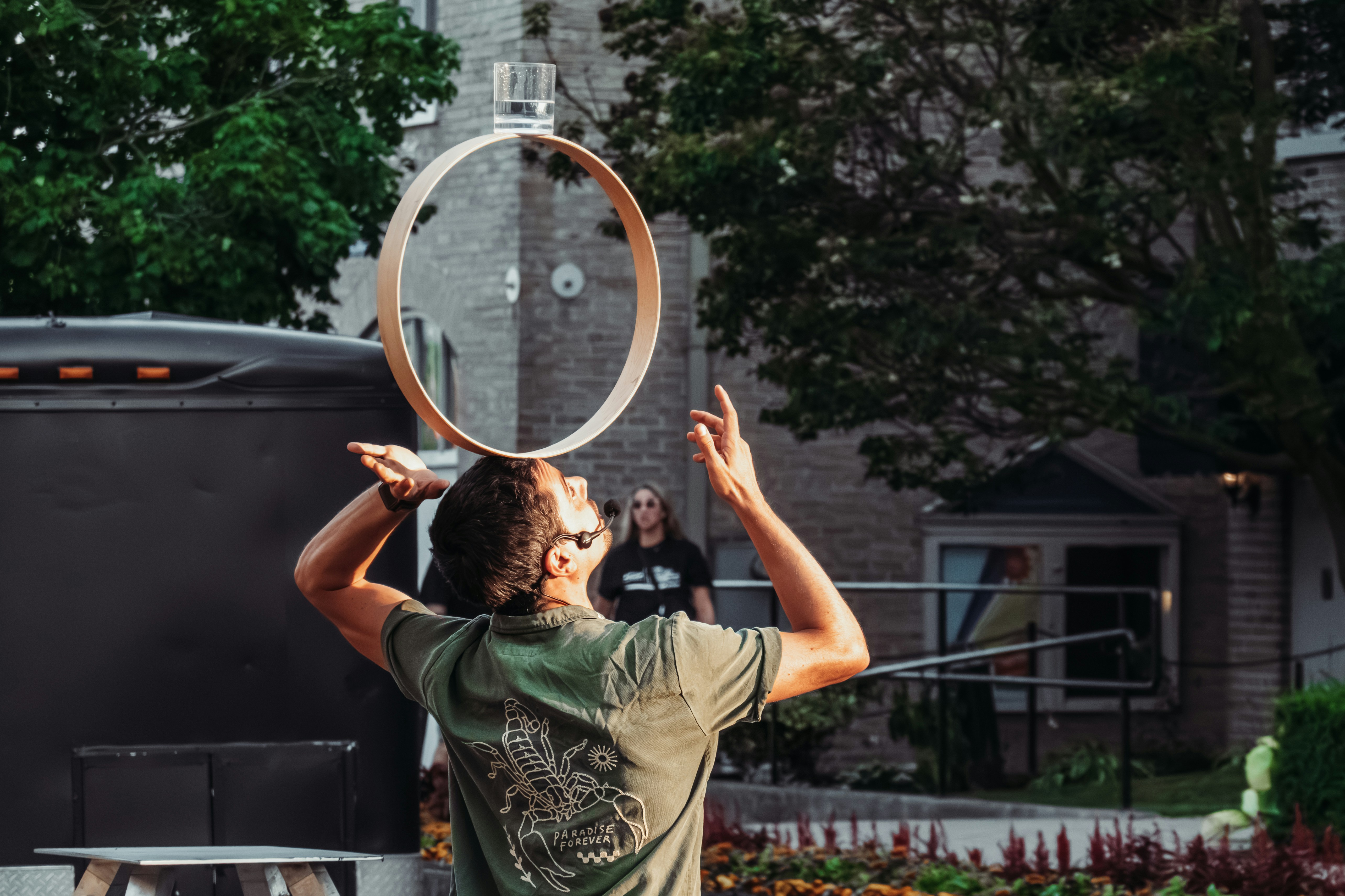 A performer balances a glass on their head.