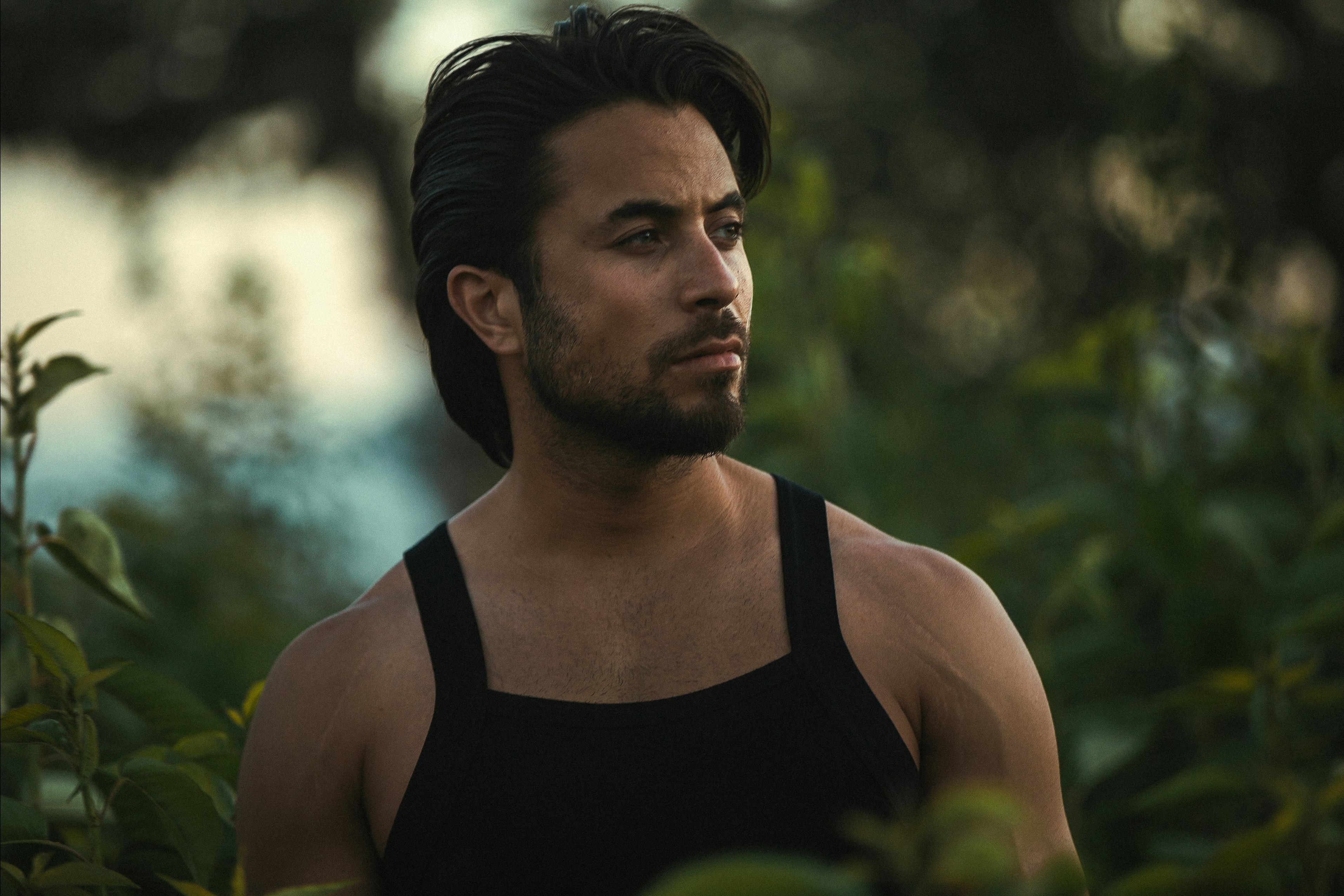 A man in a tank top gazes thoughtfully.