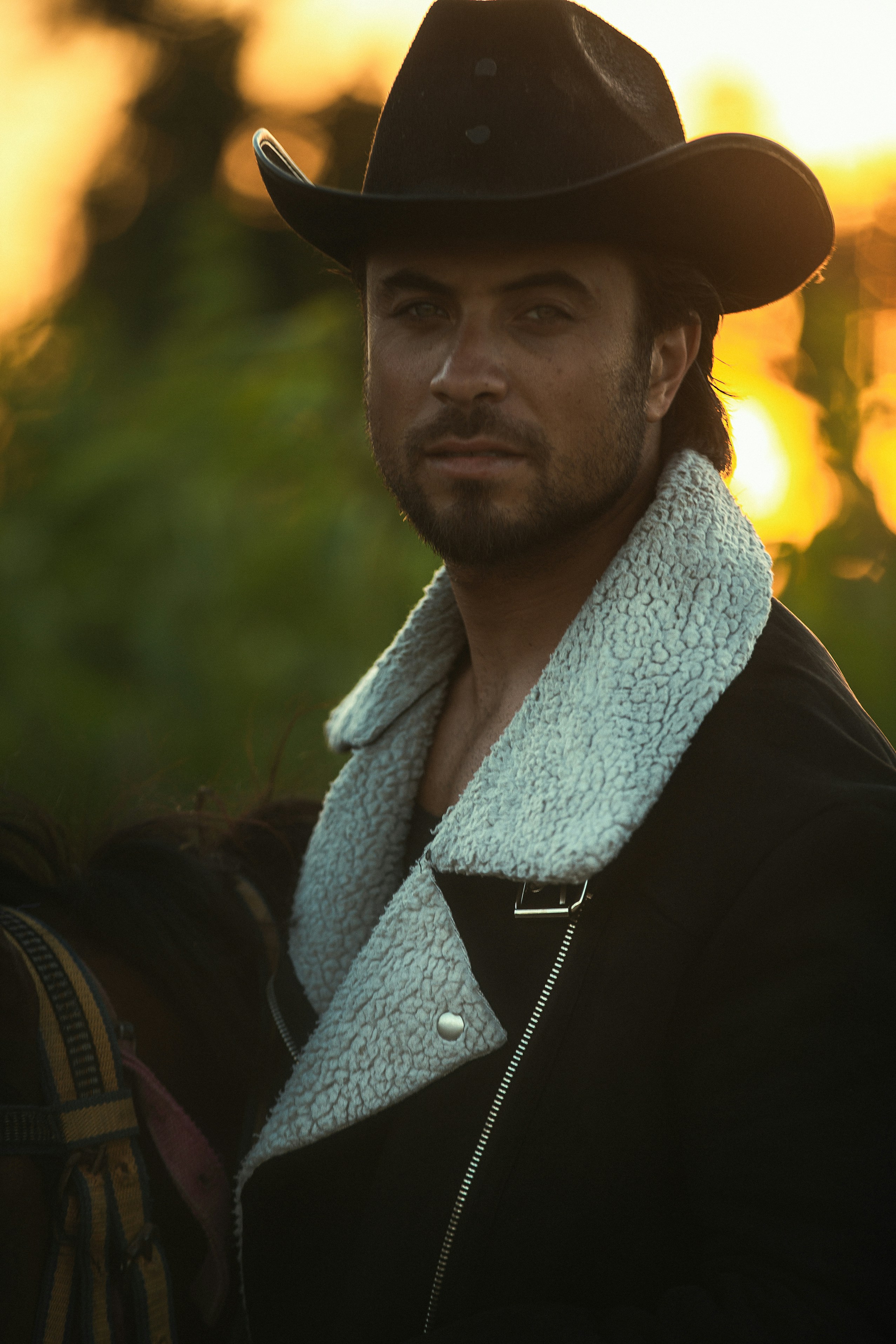 A cowboy with a hat and coat poses.