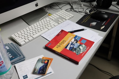A messy desk with computer and books.