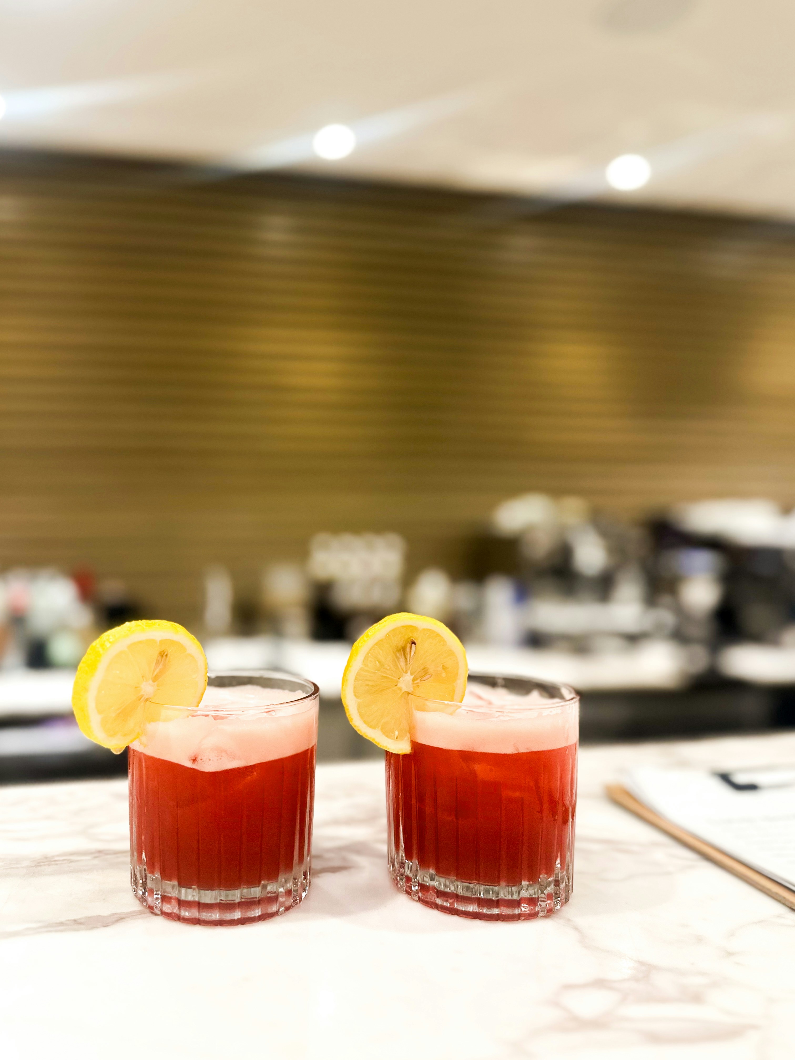 Deux cocktails avec des tranches de citron sont posés sur un comptoir.