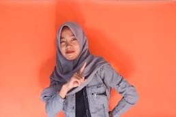 Young woman in hijab pointing finger at camera