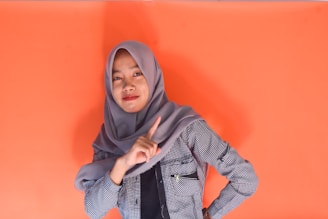 Young woman in hijab pointing finger at camera