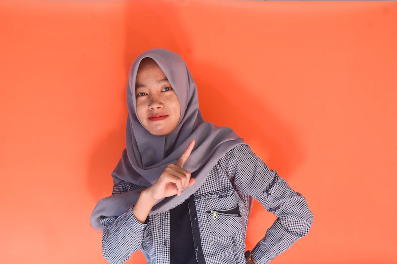 young woman in hijab pointing at camera