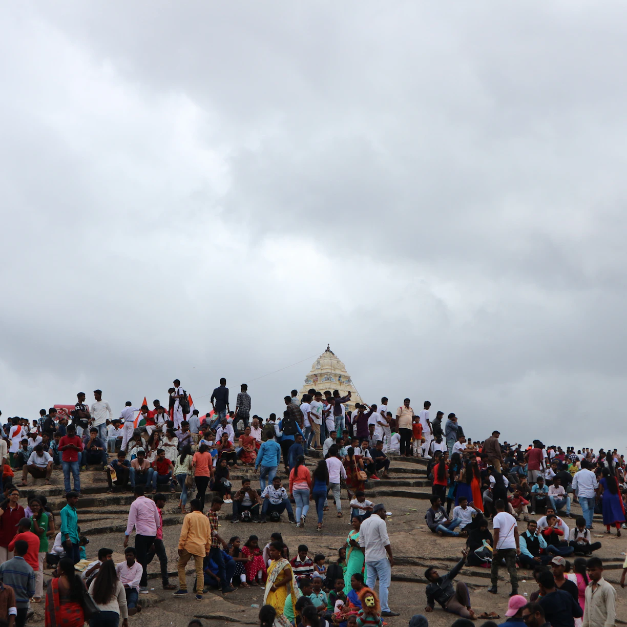 People gather near a temple on a cloudy day.