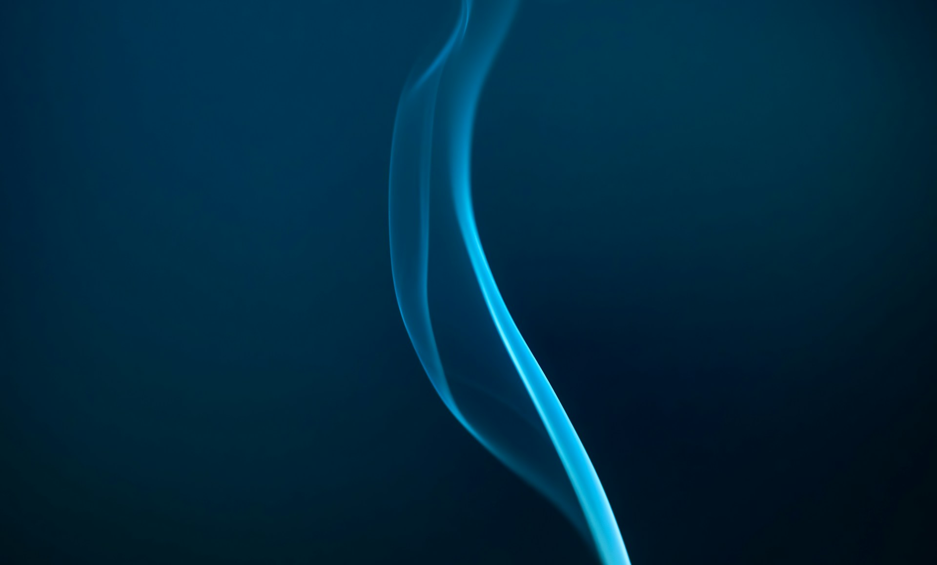 Blue smoke gracefully rising against the dark.