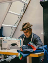 A tailor sews at his sewing machine.