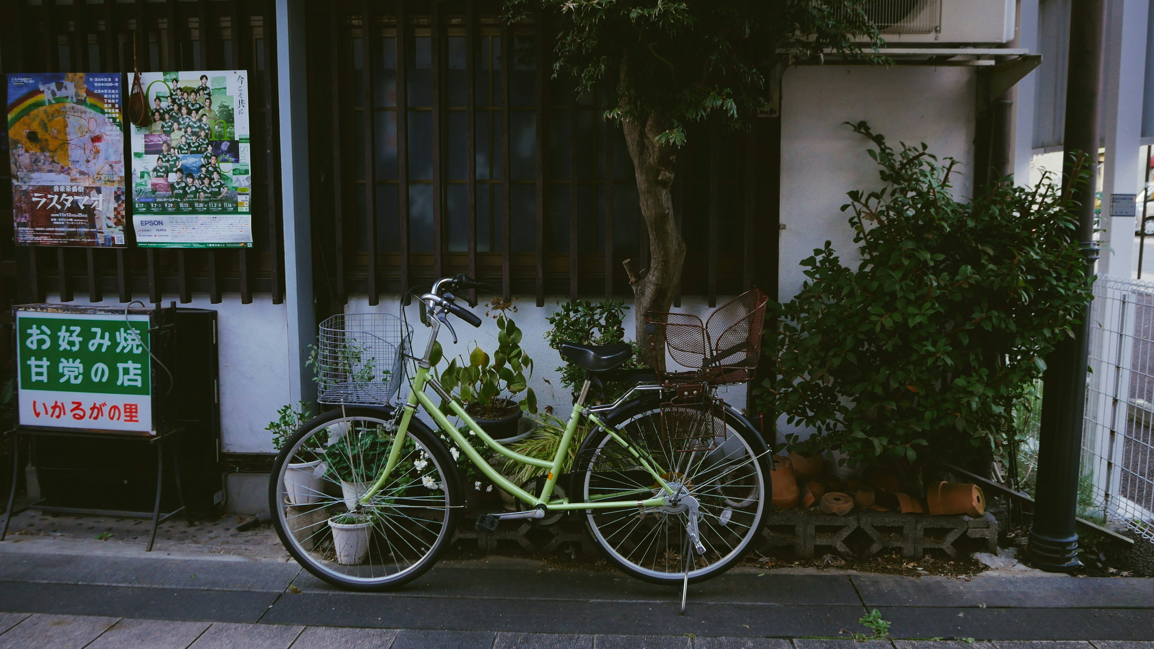 A bicycle rests against a building on a street.