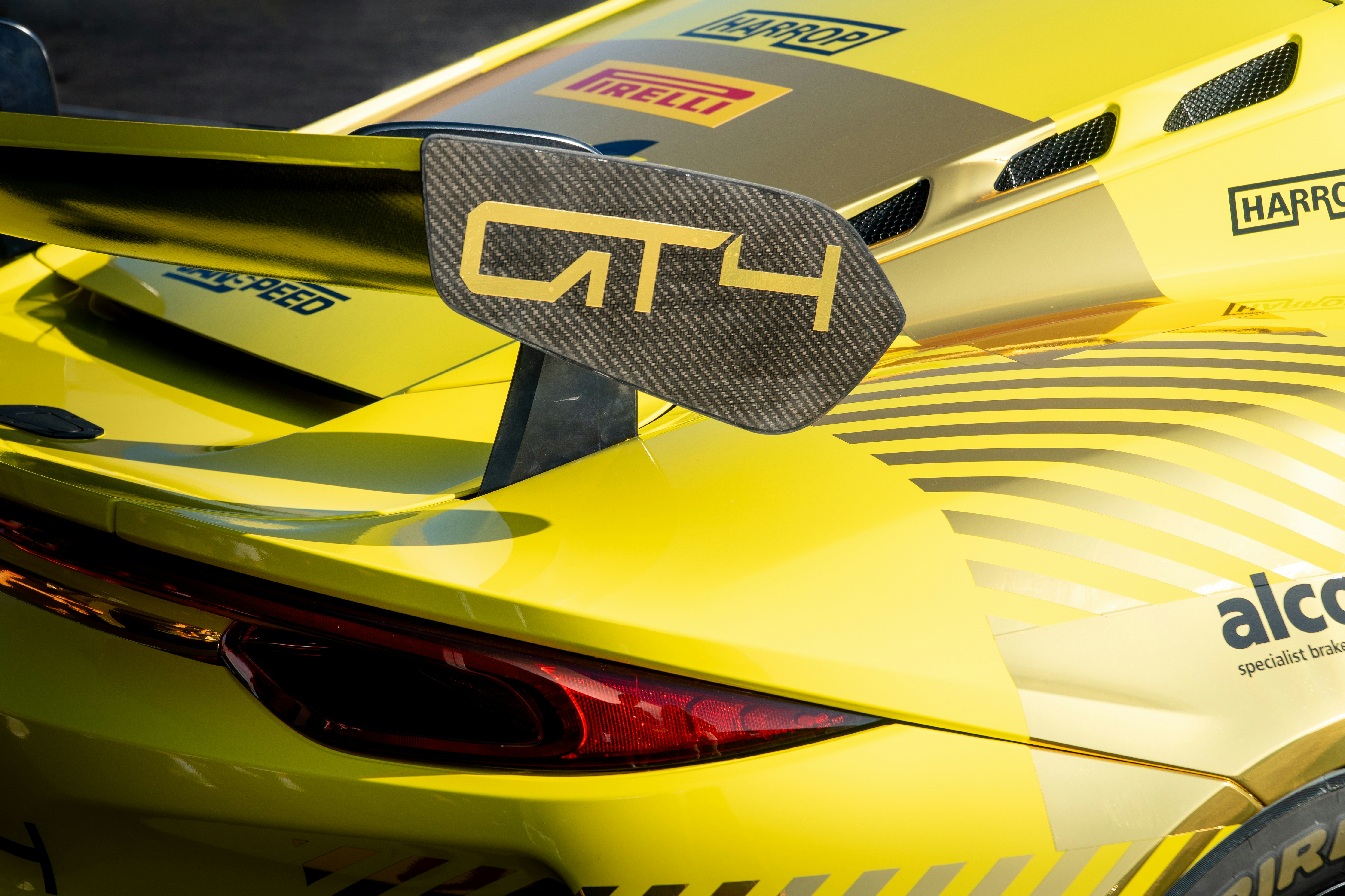 L’aileron jaune d’une voiture de course gt4 est visible.