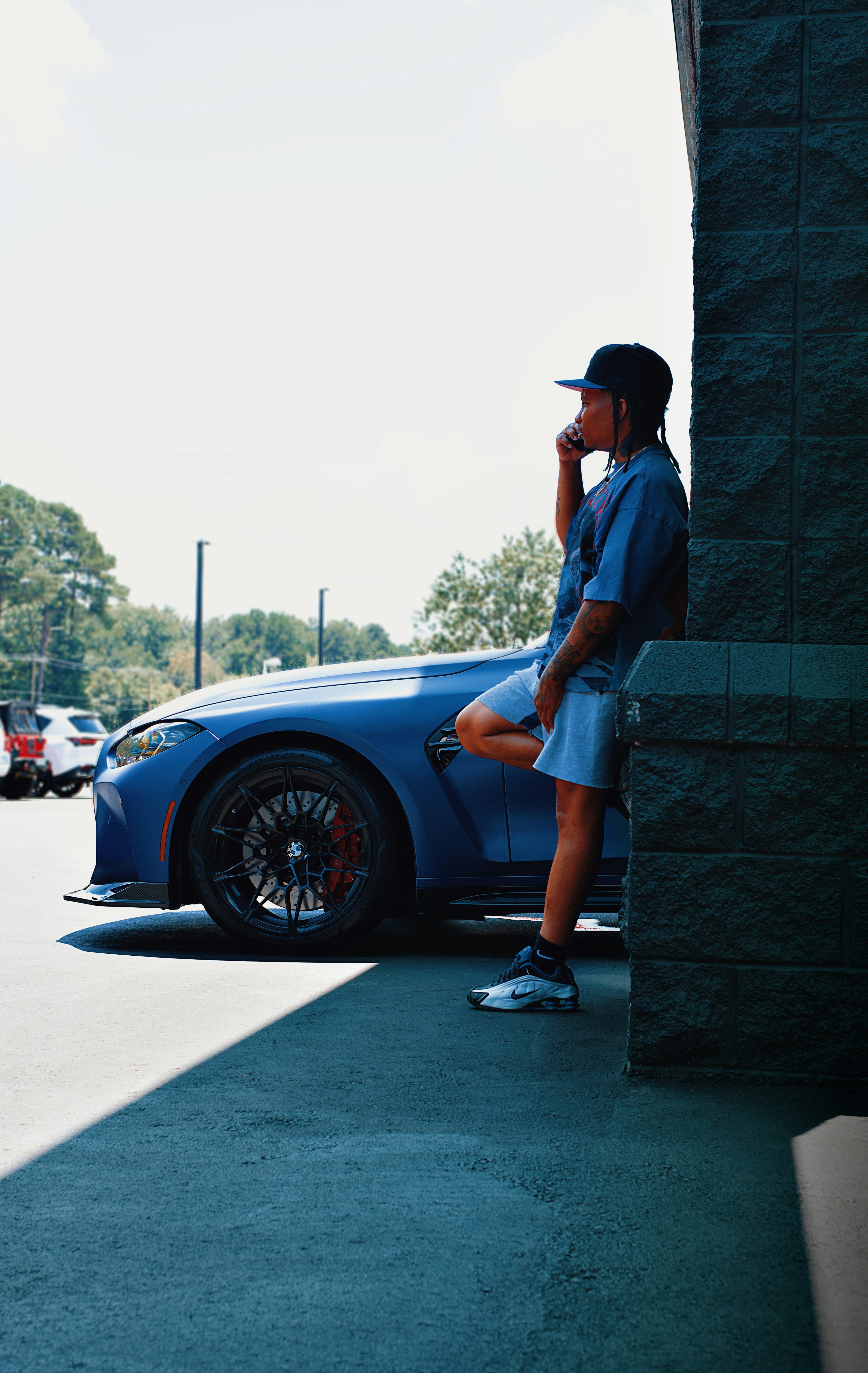 L'uomo si appoggia a un'auto, parlando al telefono.