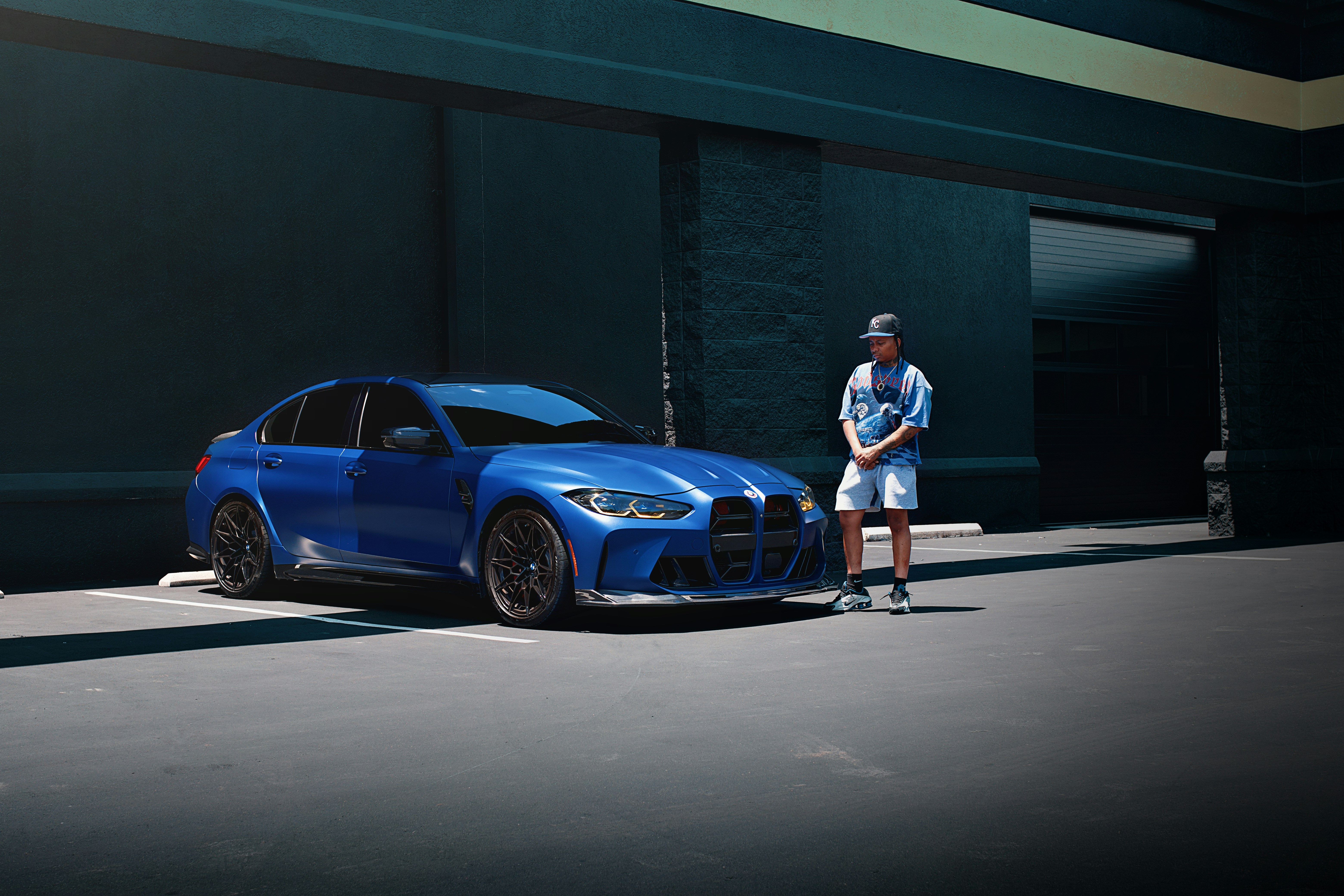 Una berlina BMW blu con un uomo in piedi accanto.