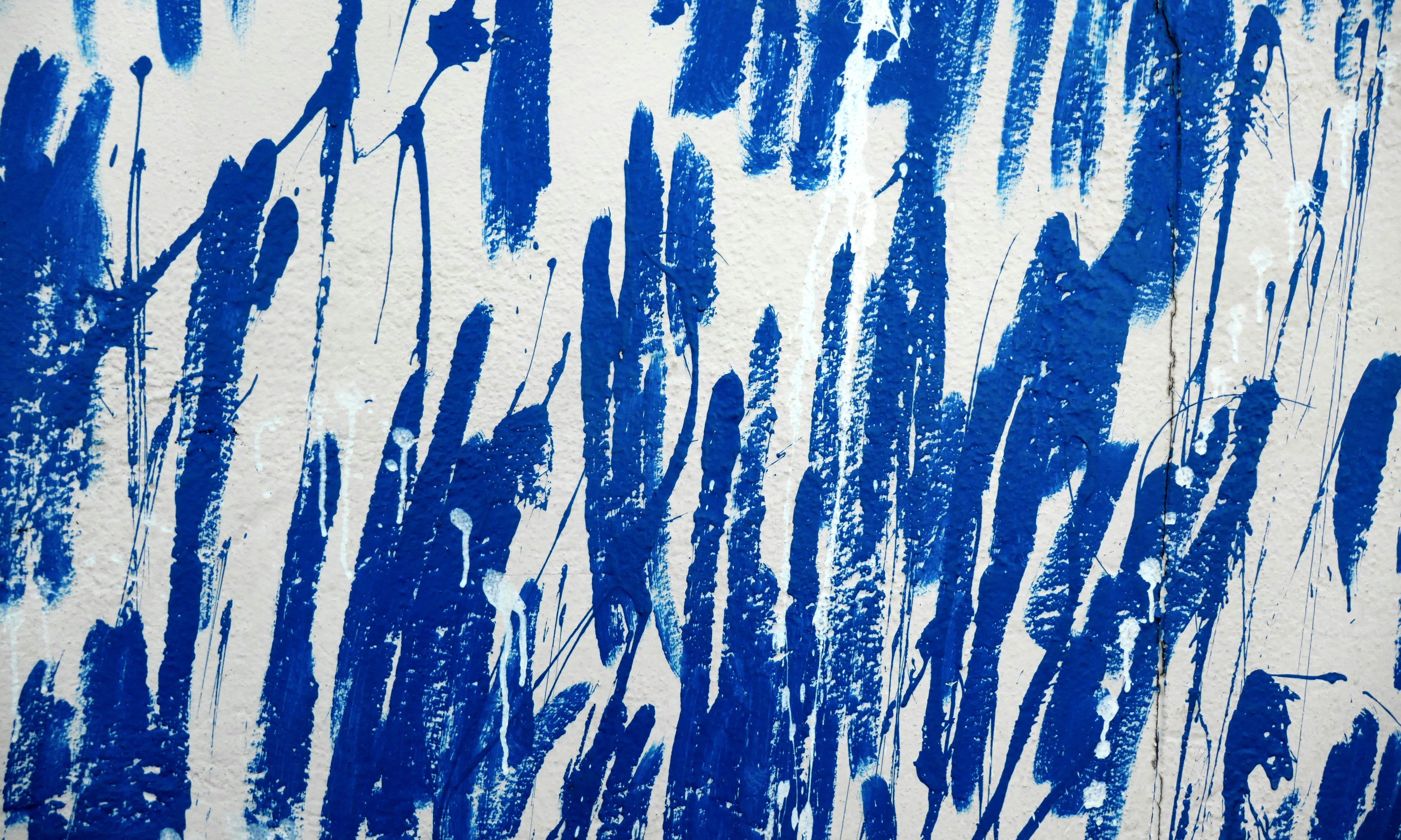 Blue paint streaks decorate a white surface.