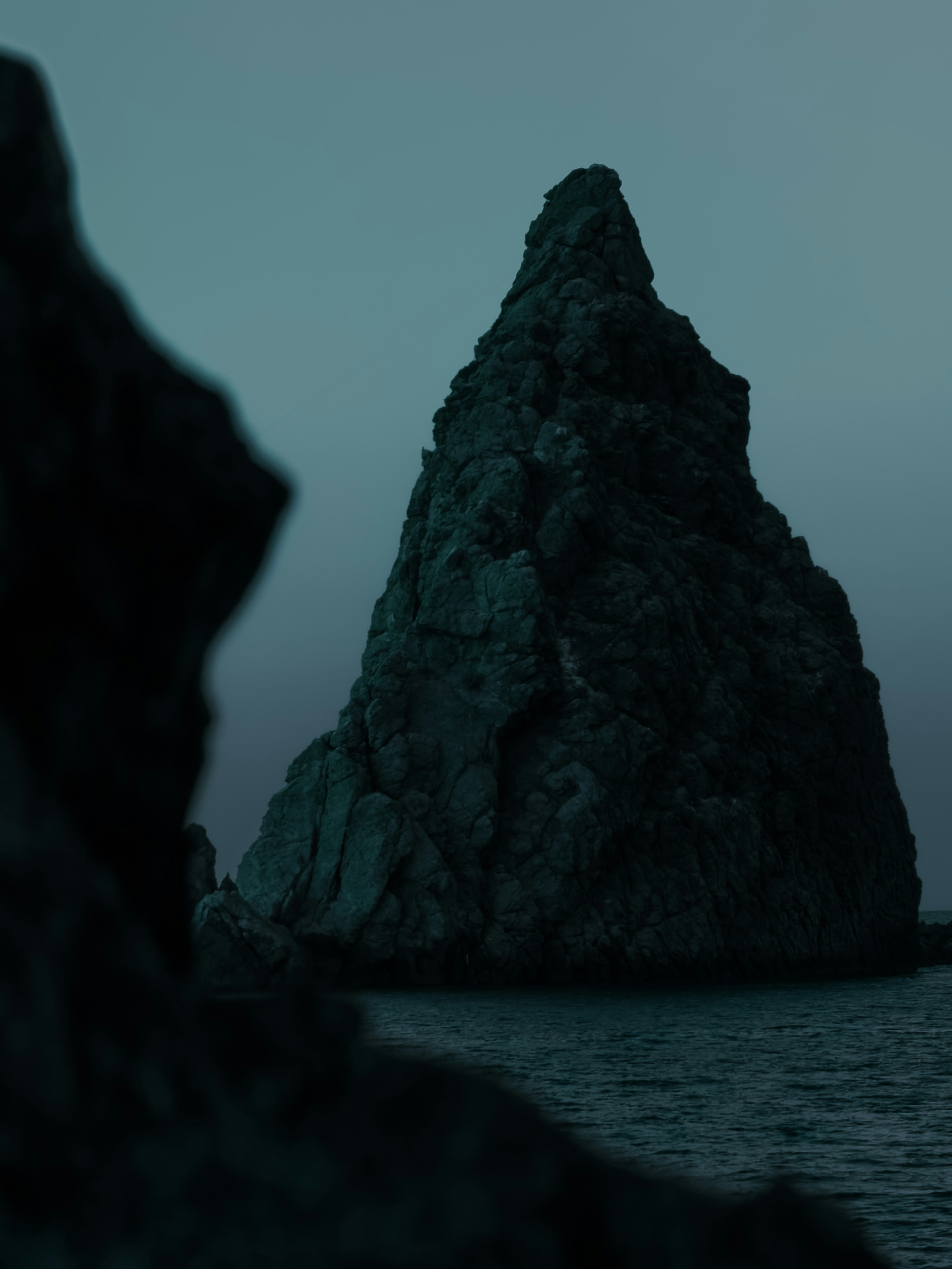 Dramatic rock formation stands in the dark sea