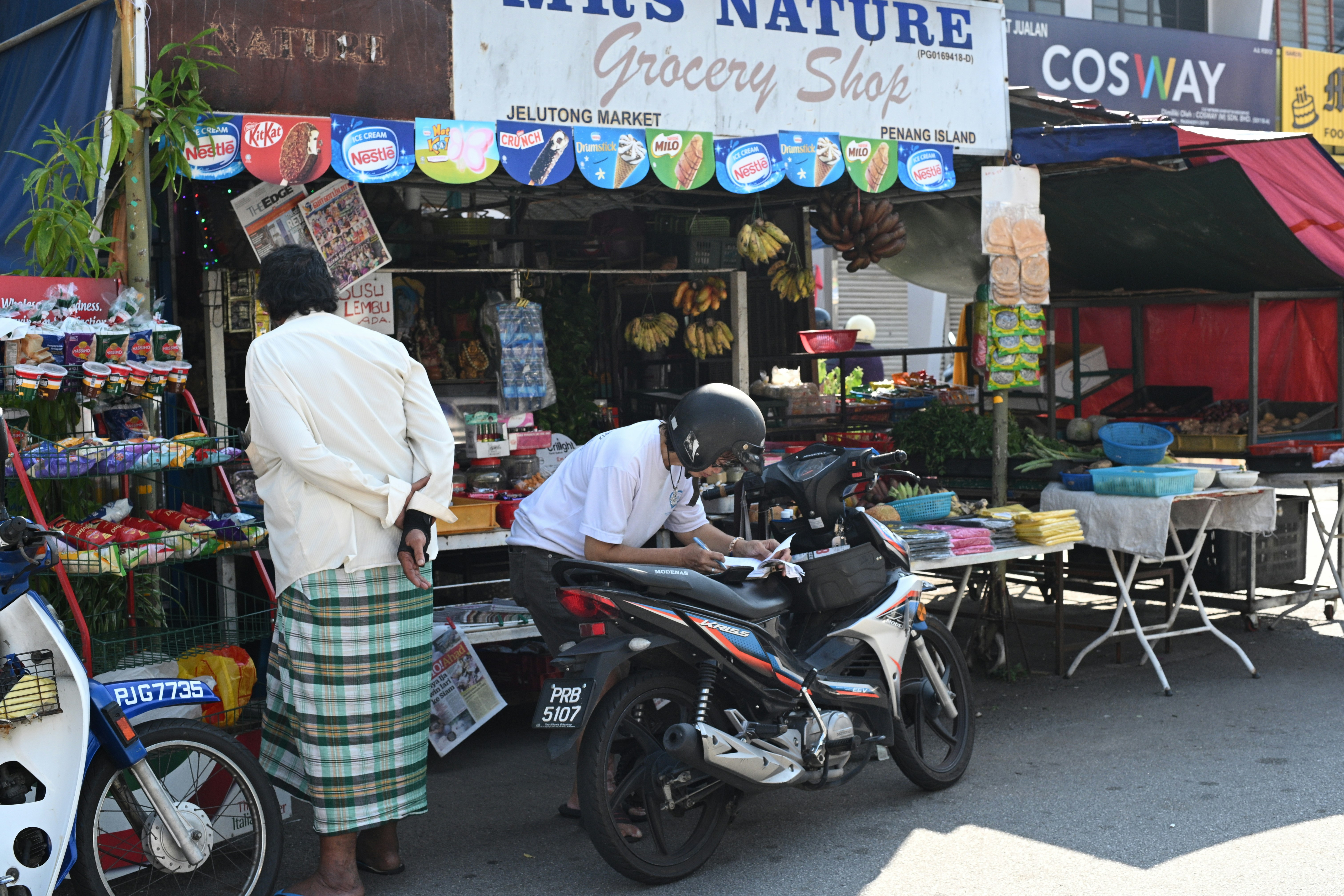 A grocery shop with people and a motorcycle outside.