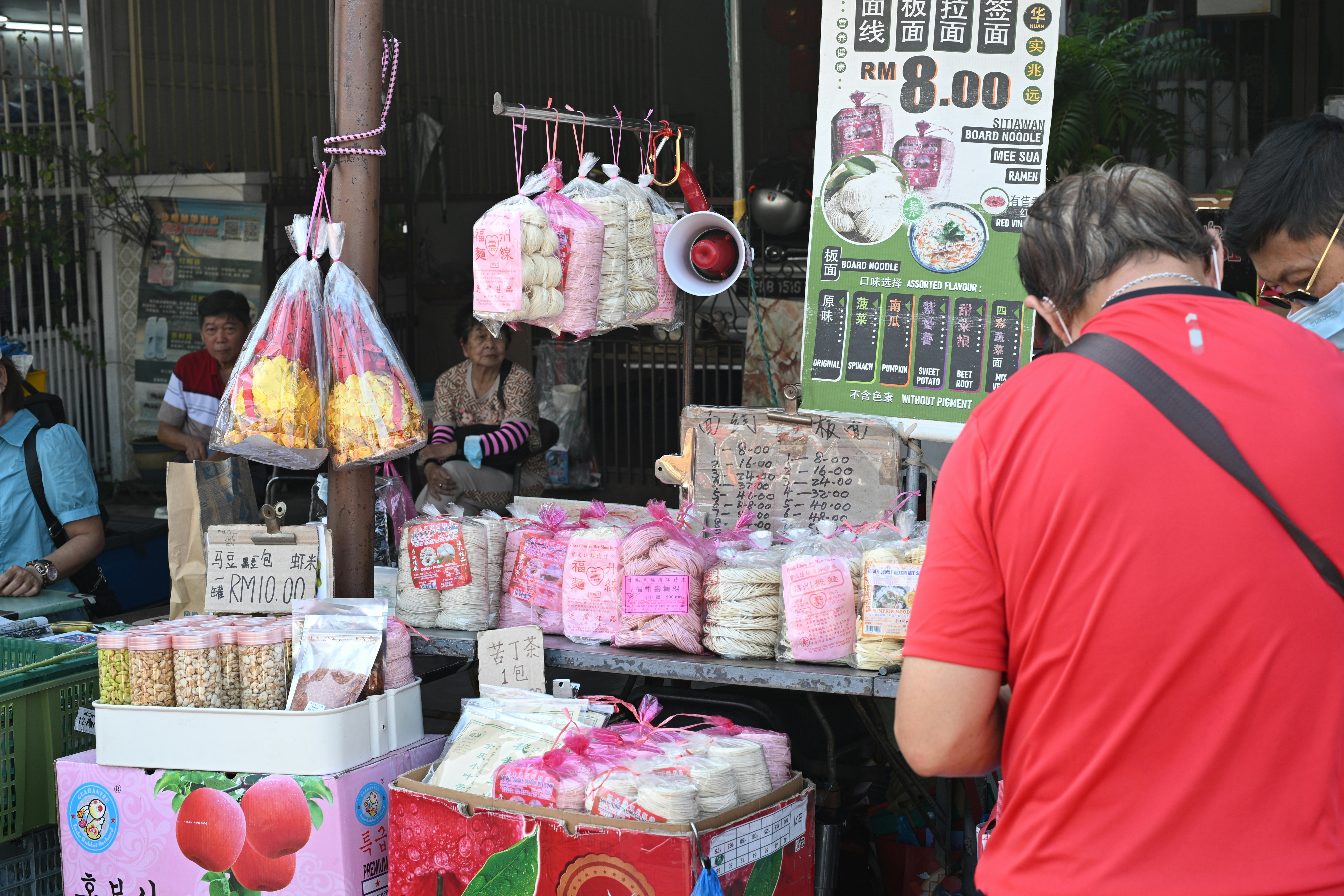 A street vendor sells packaged goods and fruit.