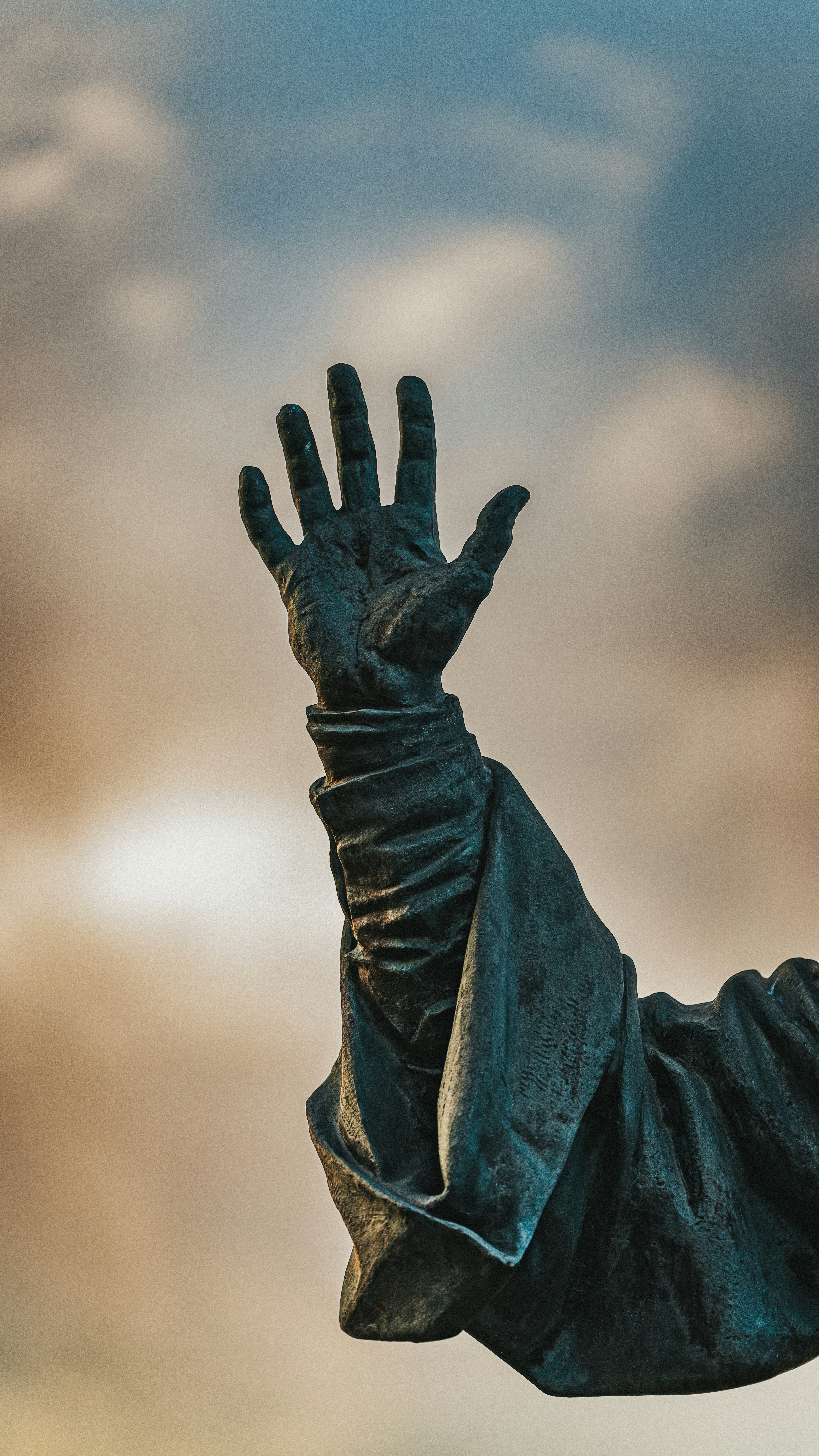 A statue hand reaches towards the sky.
