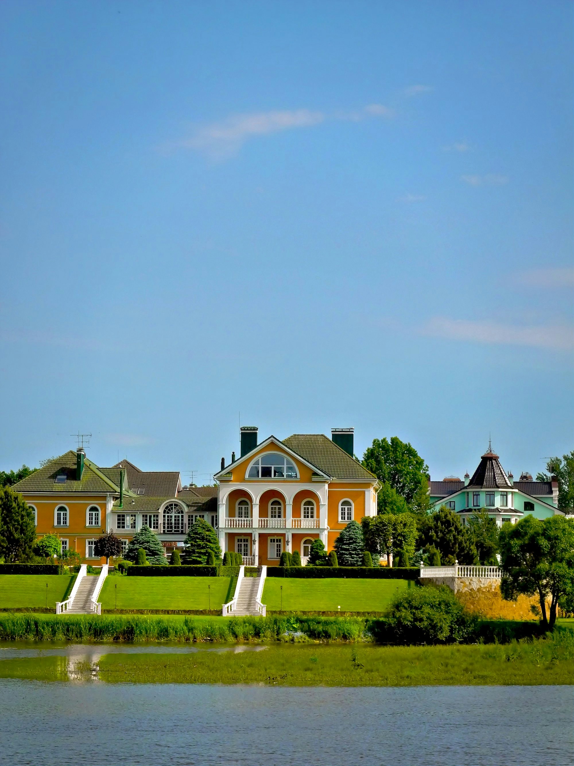 Luxurious houses line a waterfront on a sunny day.