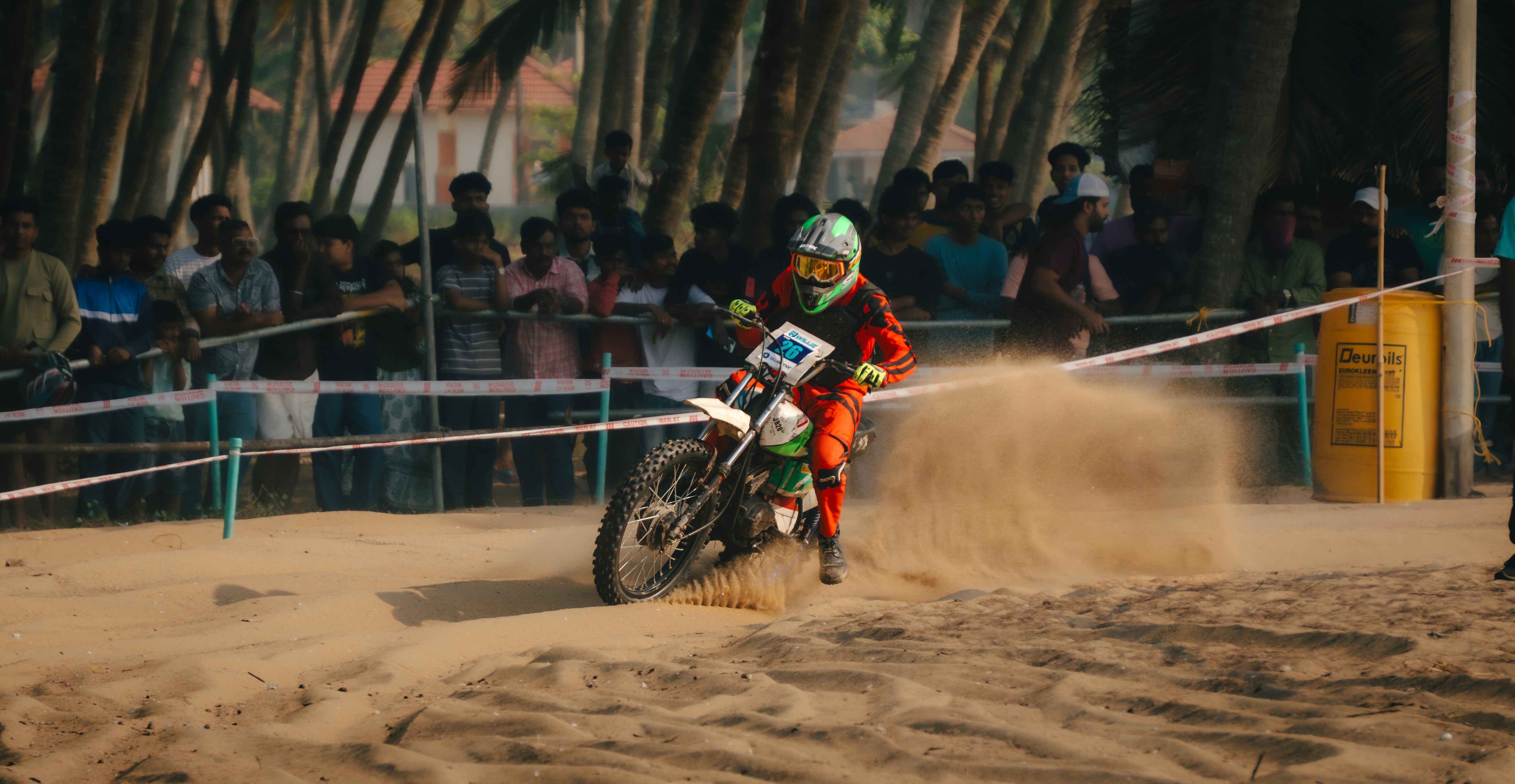 Seorang pengendara motocross menendang pasir saat balapan.