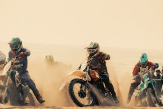 Motorcycle riders race on a sandy track.