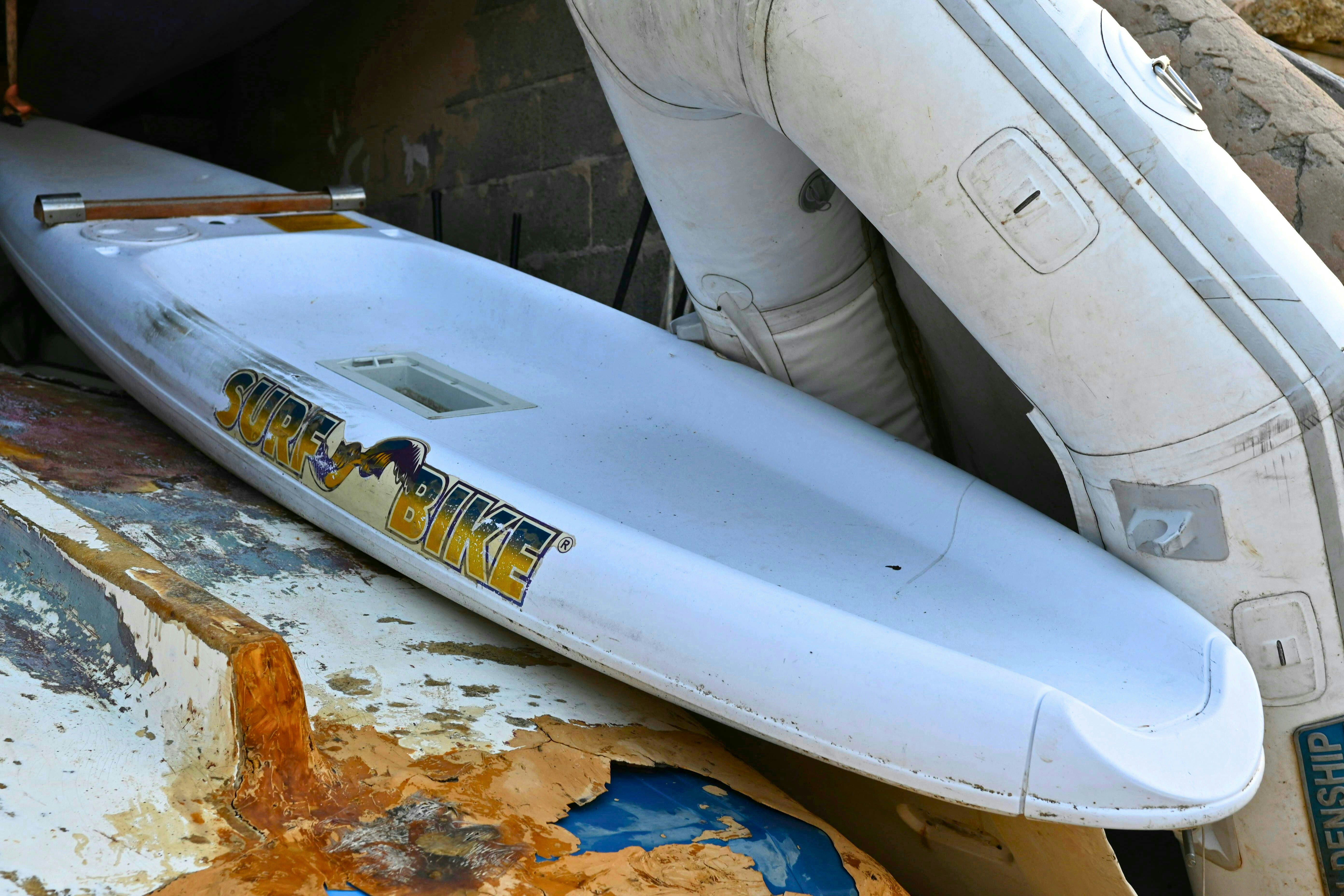 A white surfboard is seen with a dinghy.