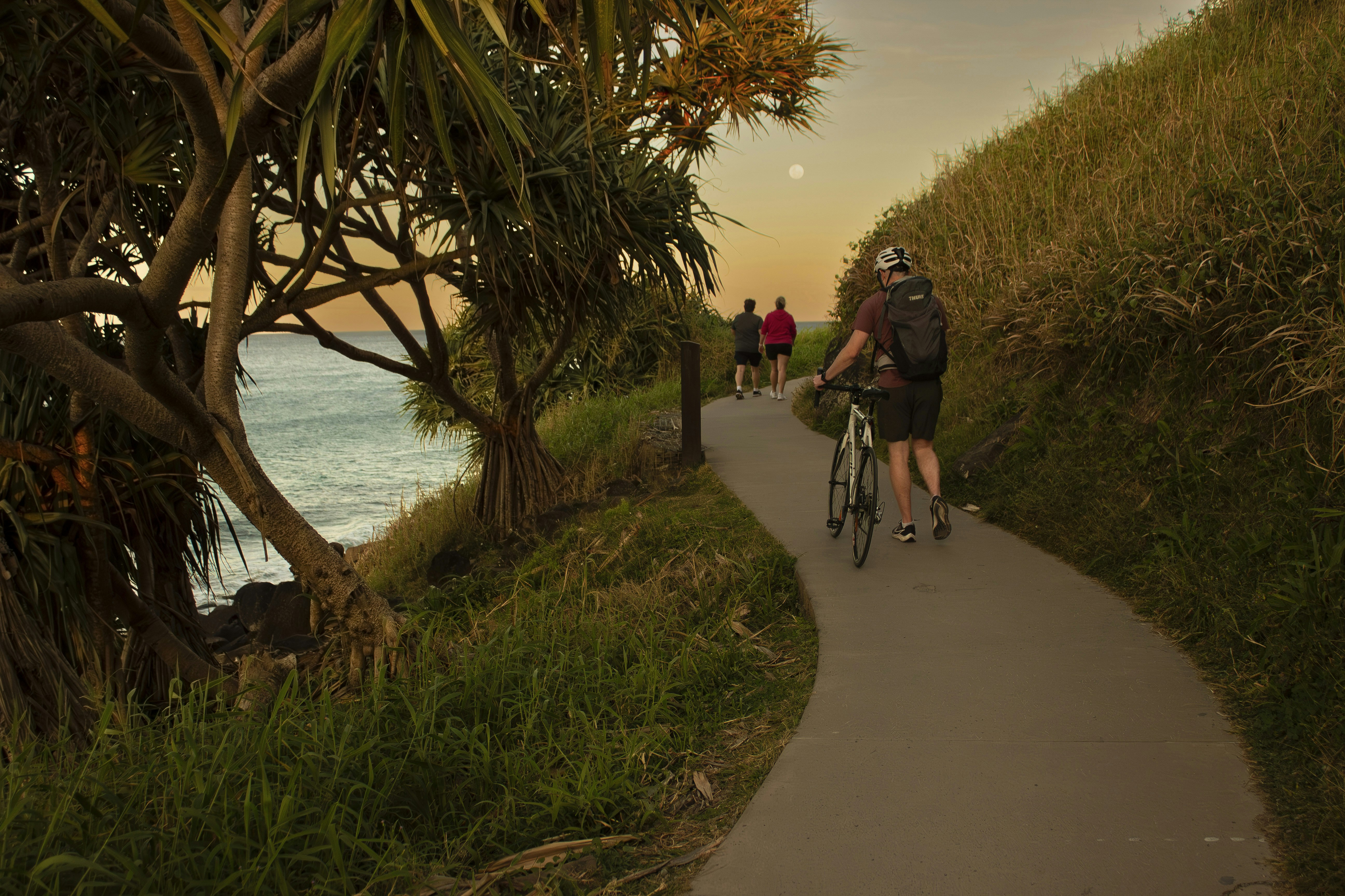 Cyclist rides along coastal path at sunset.