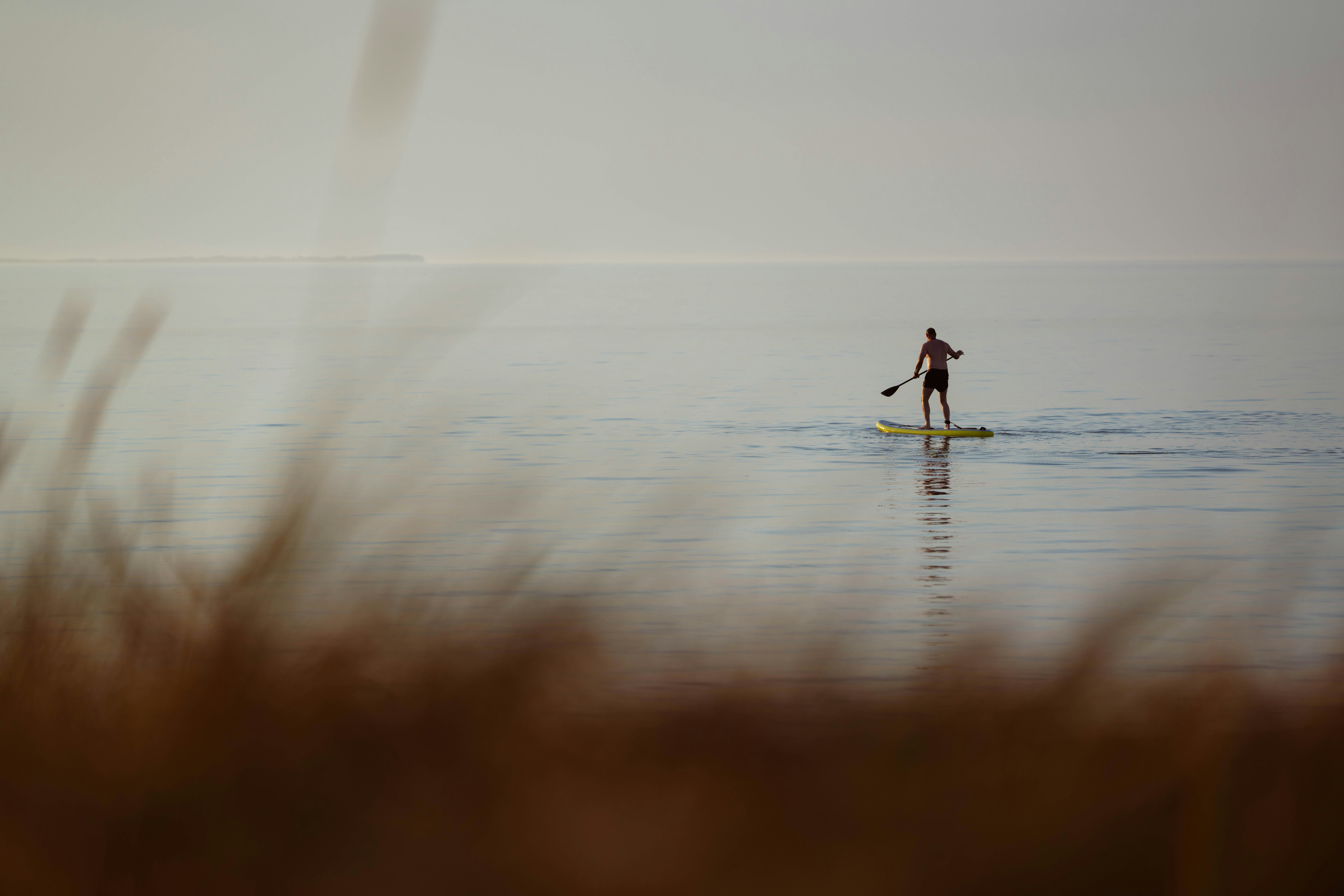 Mann paddelt mit einem Stand-Up-Board im Wasser.