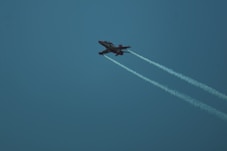 A fighter jet flies through a bright, blue sky.