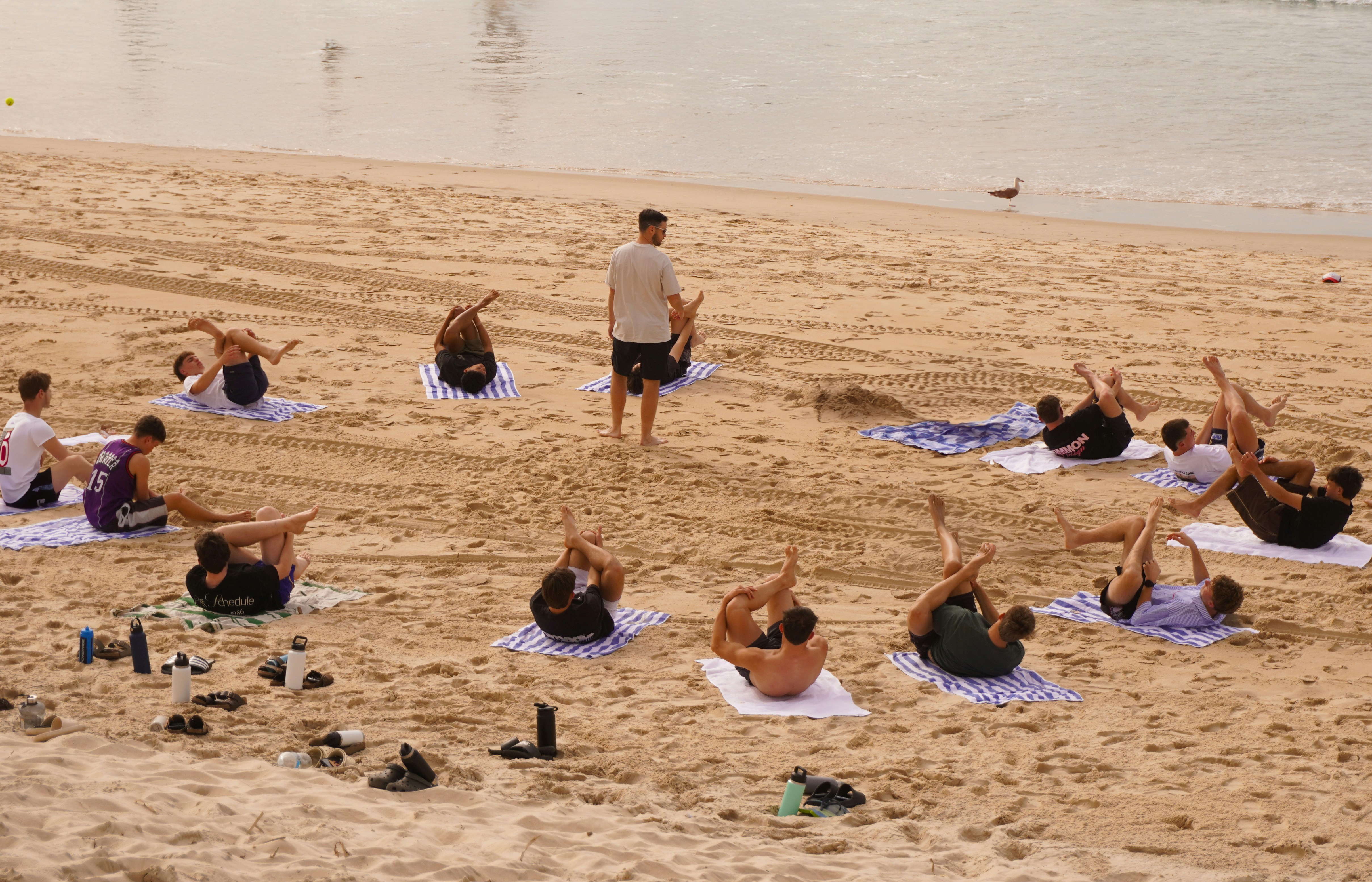 People are doing yoga exercises on the beach.