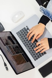 Hands typing on a laptop and looking at the screen.
