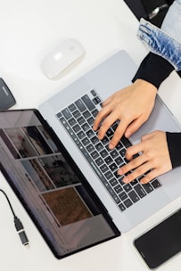 Hands typing on a laptop and looking at the screen.