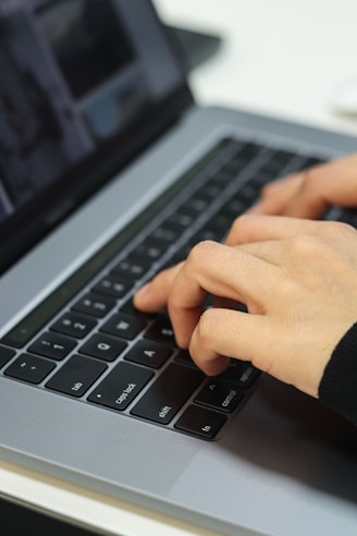 Hands type on a laptop keyboard.