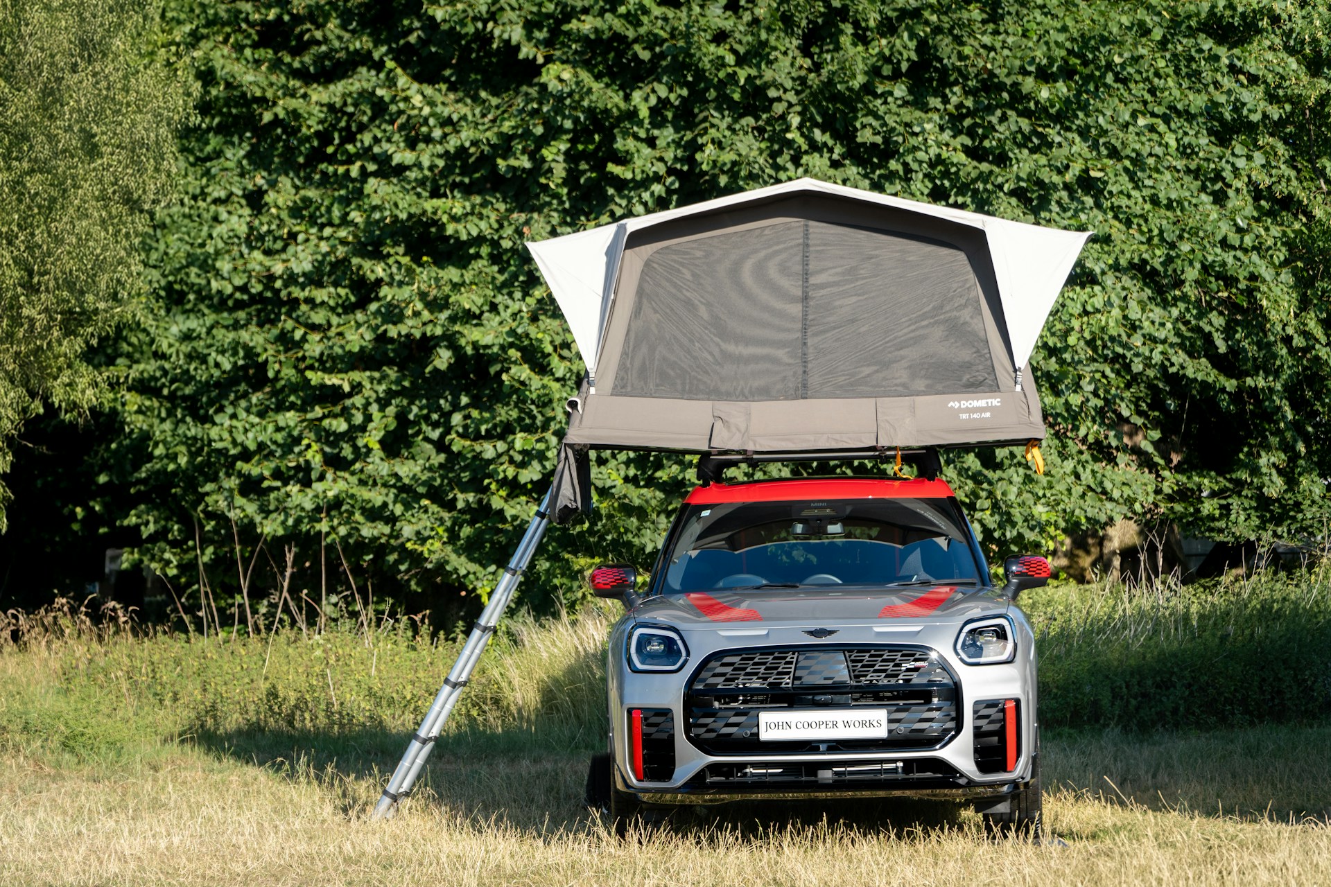 A car with a rooftop tent is camped outdoors.