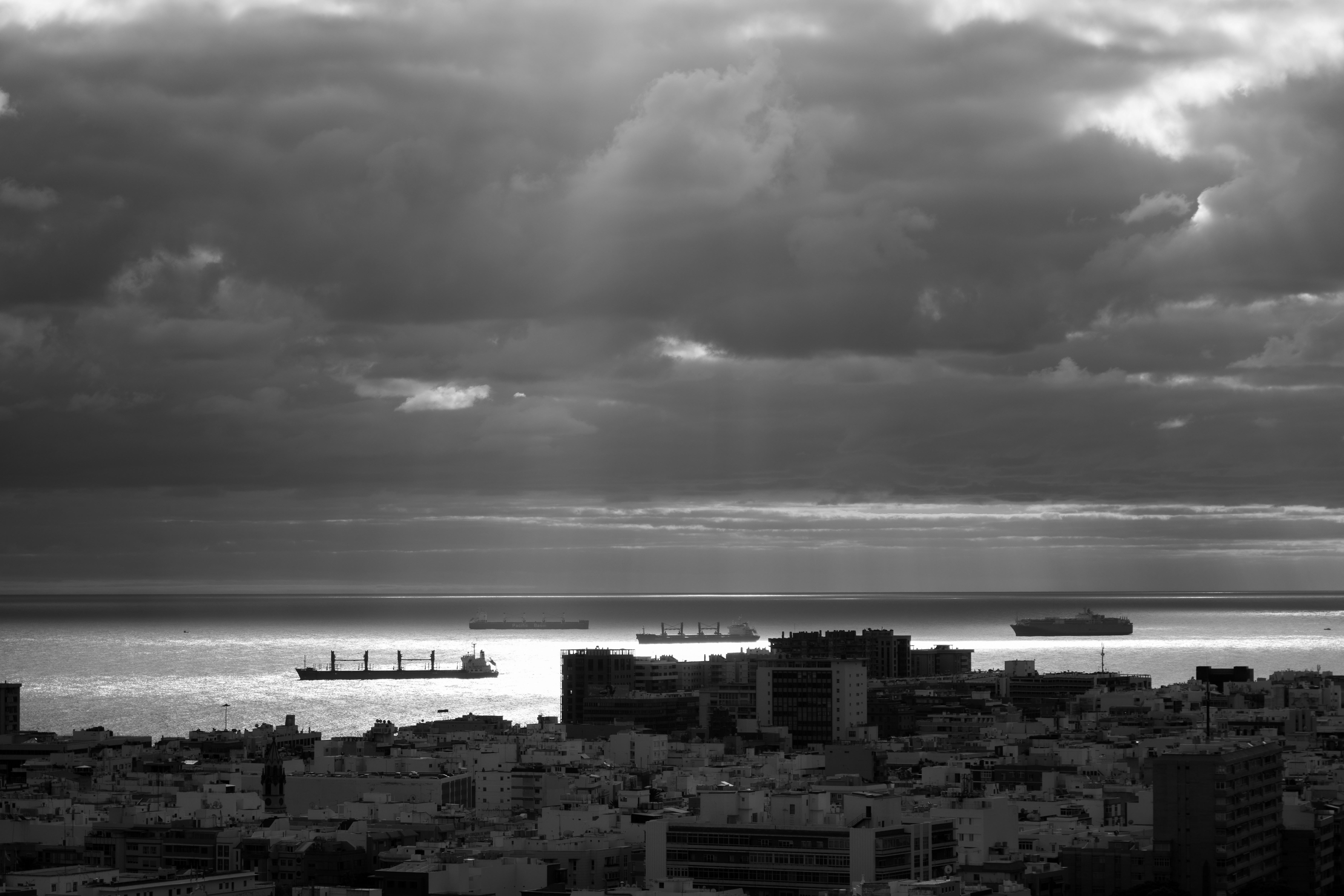 Dark clouds loom over a city and ocean.