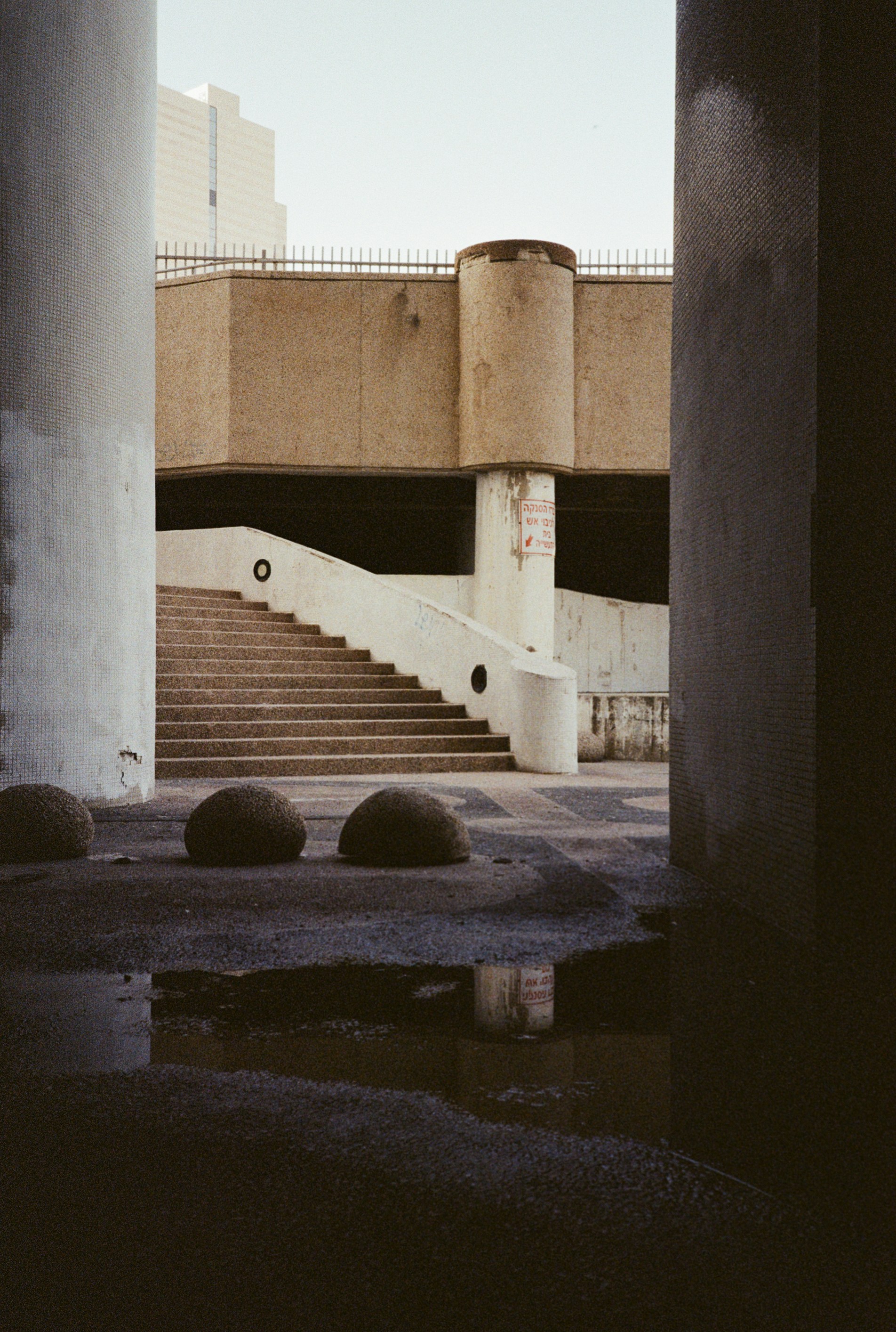 Concrete architecture is reflected in a puddle.