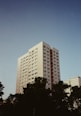 A tall apartment building stands beneath a clear sky.