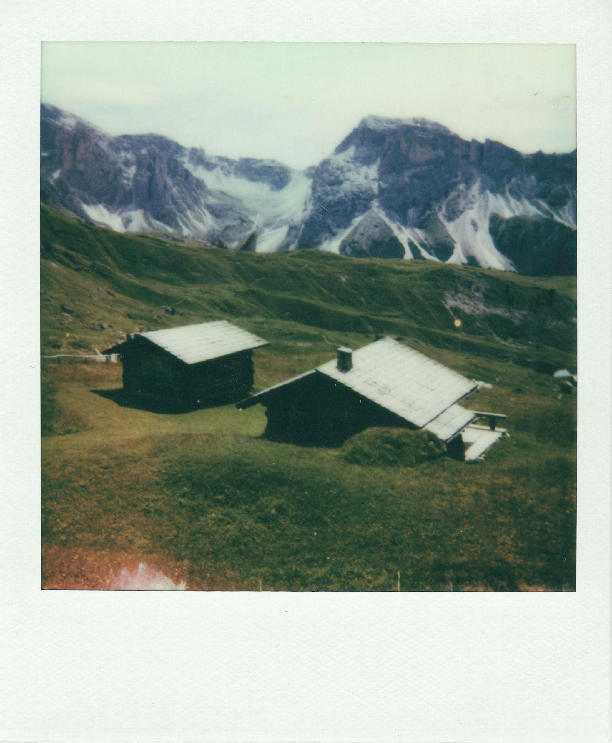 Two wooden huts stand with mountainous views