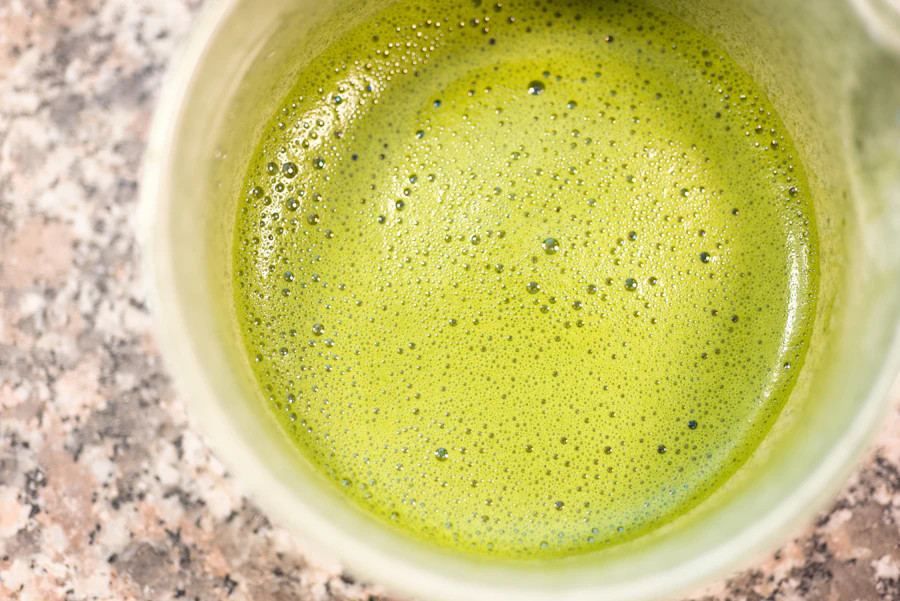 A finished bowl of bright green whisked matcha