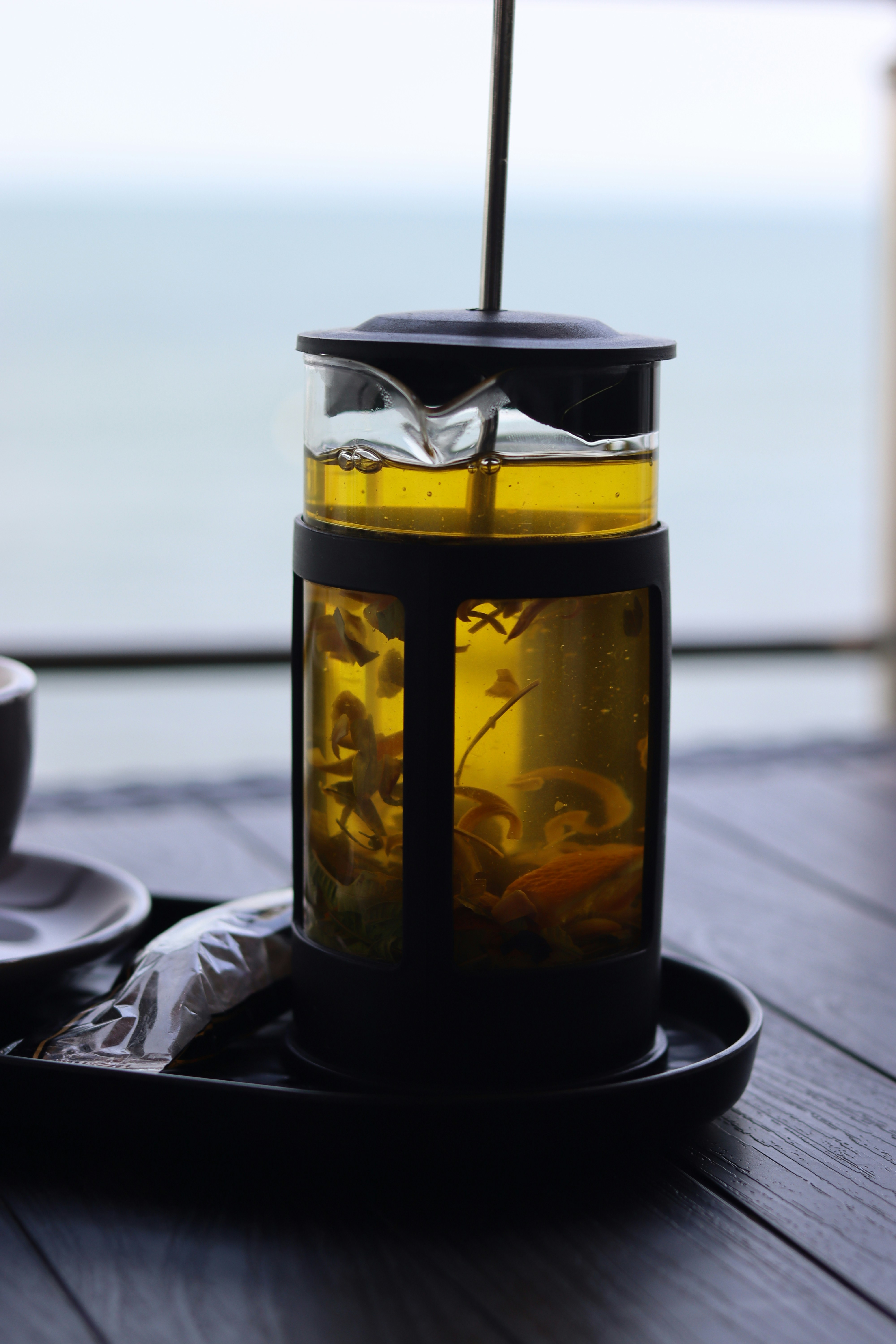 Herbal tea steeps in a french press by the sea.